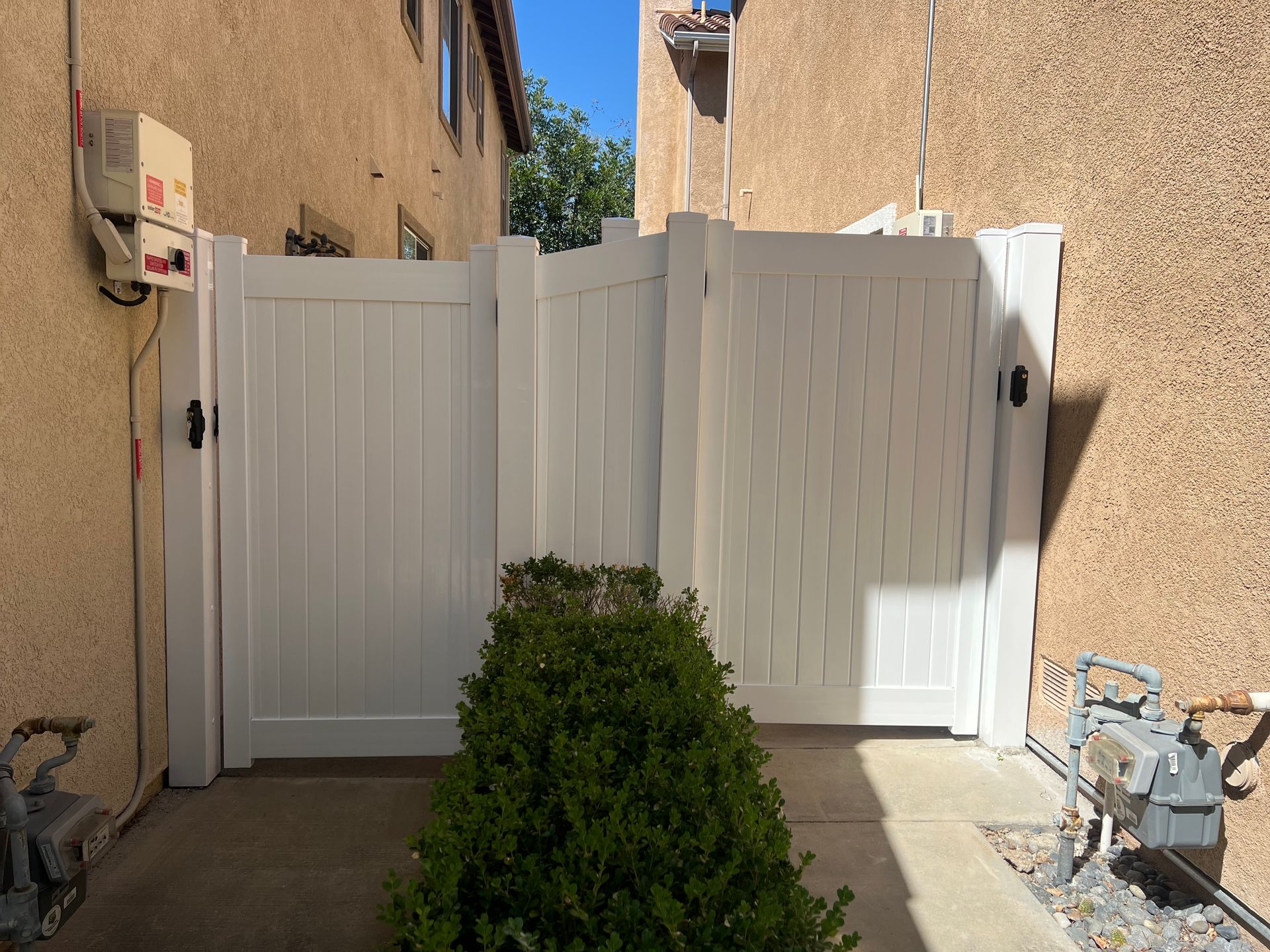 A white fence with a gate in front of a building.