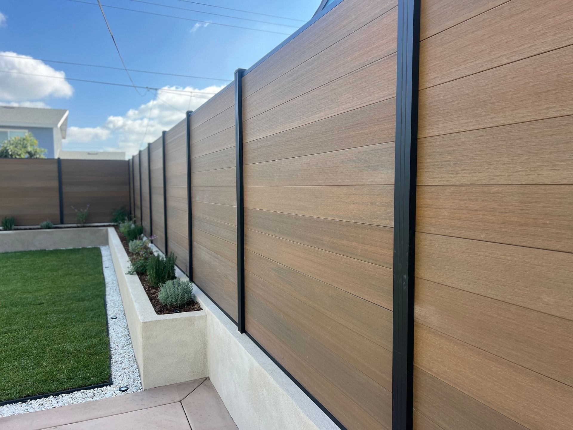 A wooden fence surrounds a lush green yard