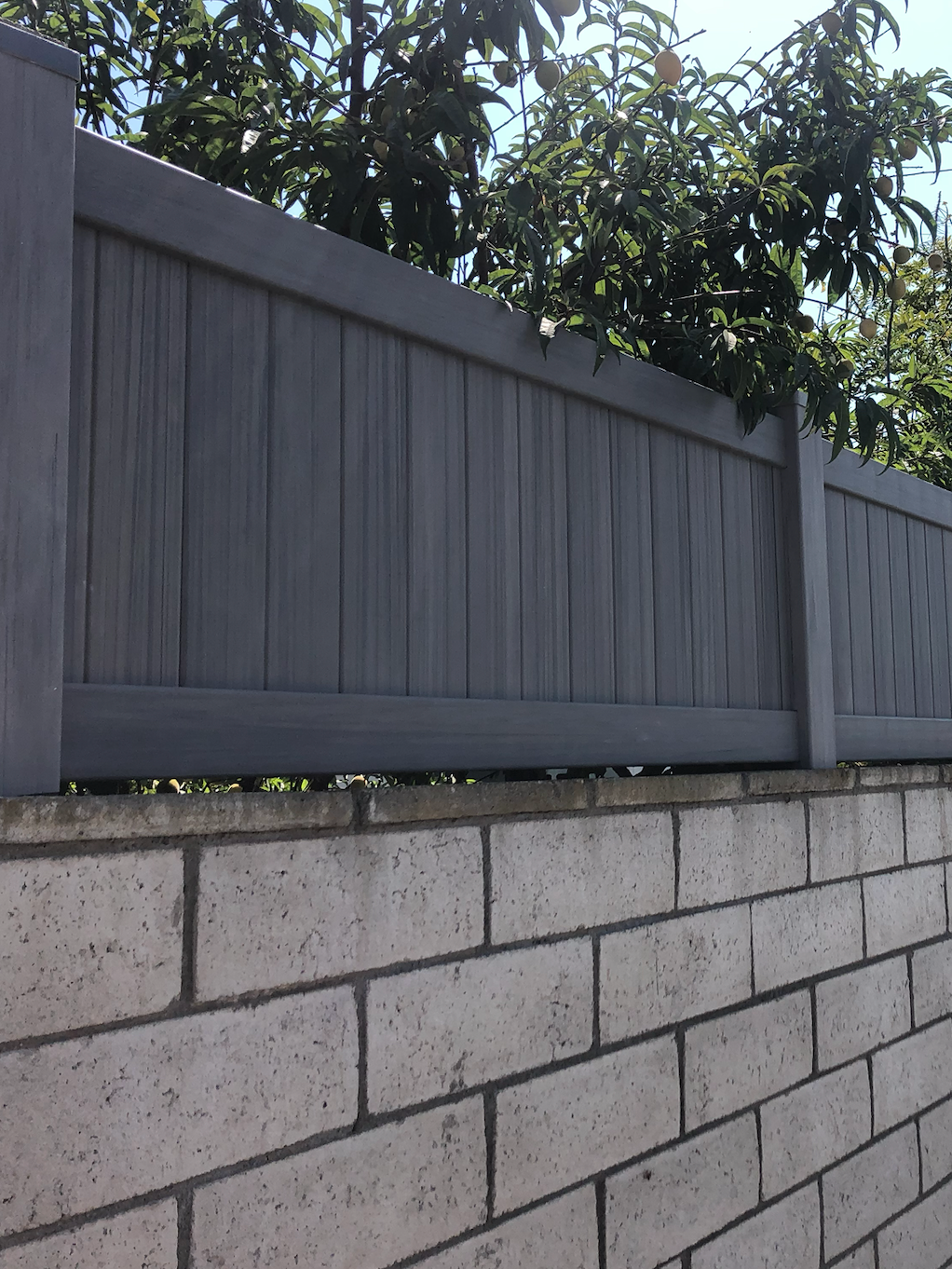 dark grey vinyl fence on top of brick wall