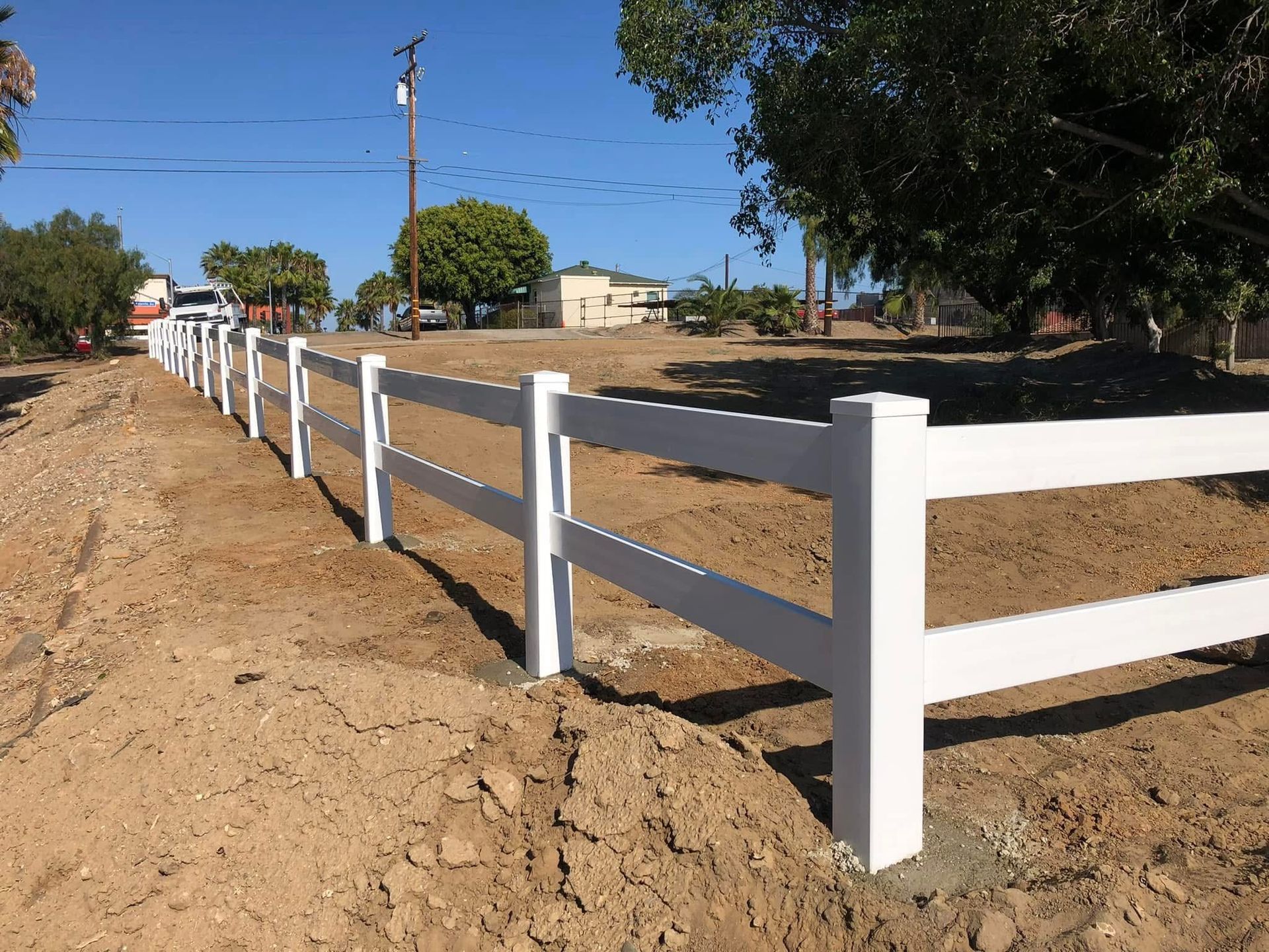 A white fence is sitting in the middle of a dirt field.
