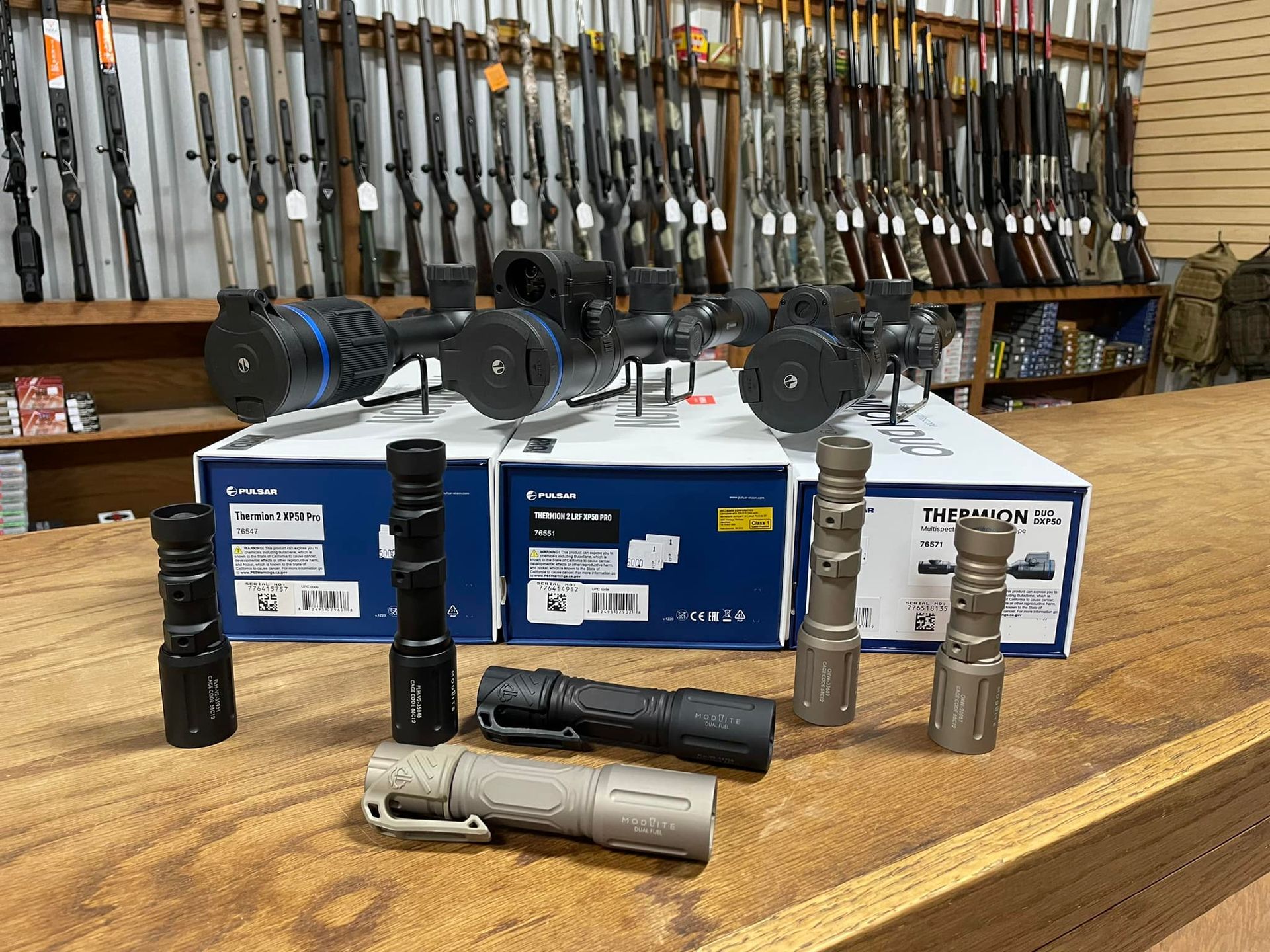 A bunch of flashlights are sitting on a wooden table in a store.