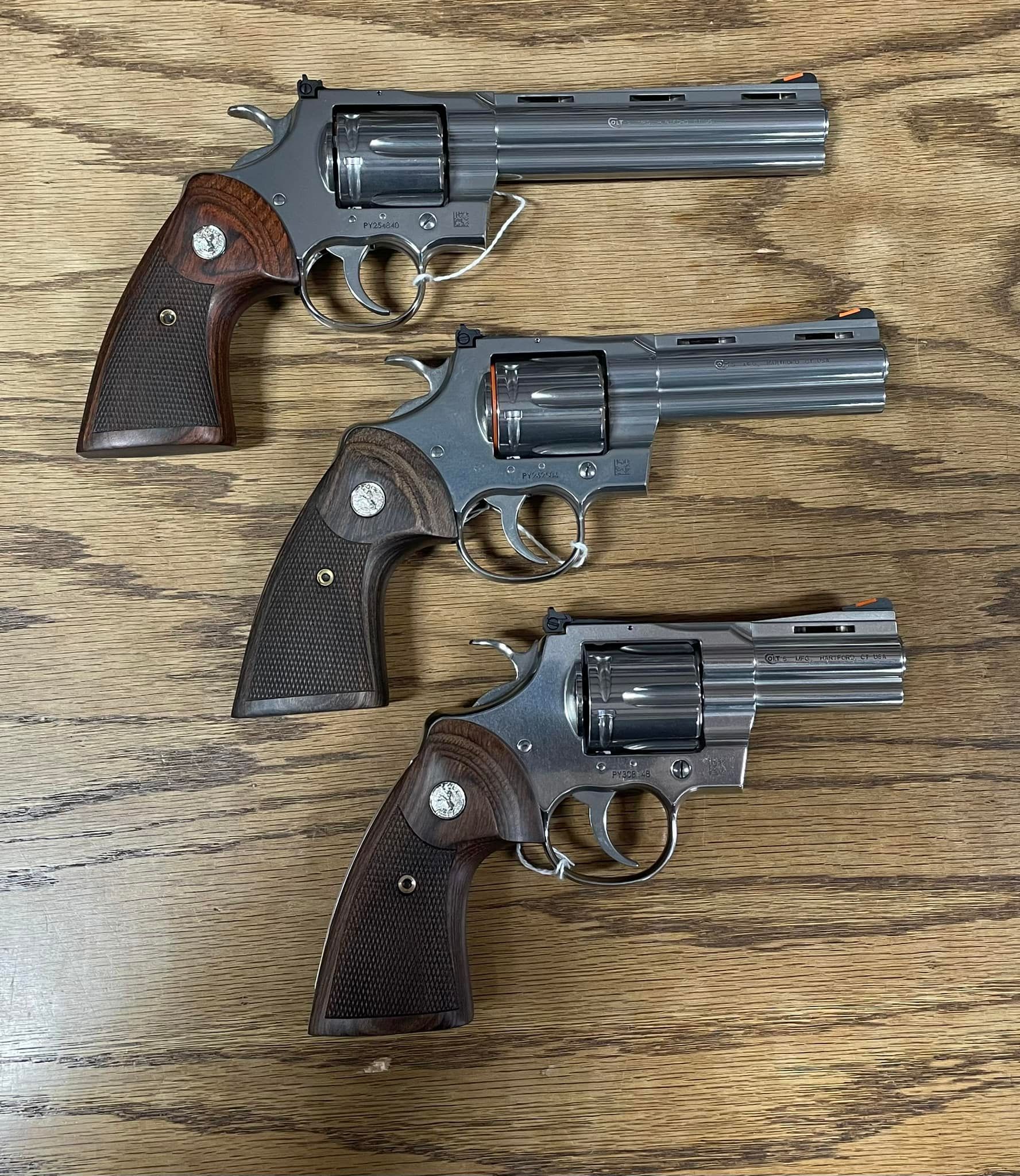 Three revolvers are sitting on a wooden table.