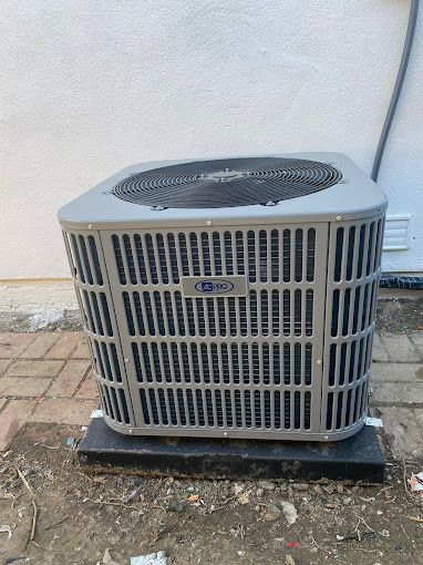 A large air conditioner is sitting on the ground outside of a building.