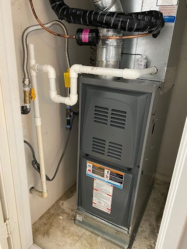 A gas furnace is sitting in a room next to a door.