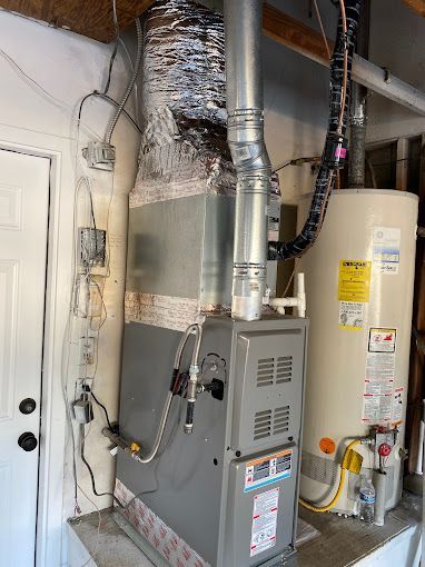 A gas heater and a water heater are sitting next to each other in a garage.