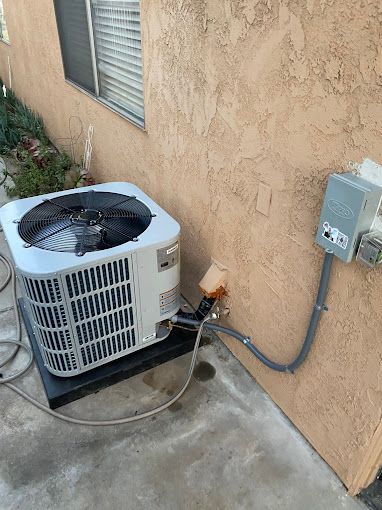 An air conditioner is sitting on the side of a building next to a window.