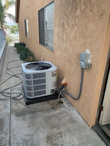An air conditioner is sitting on the sidewalk next to a building.