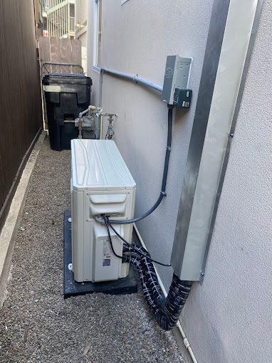 A white air conditioner is sitting on the side of a building.