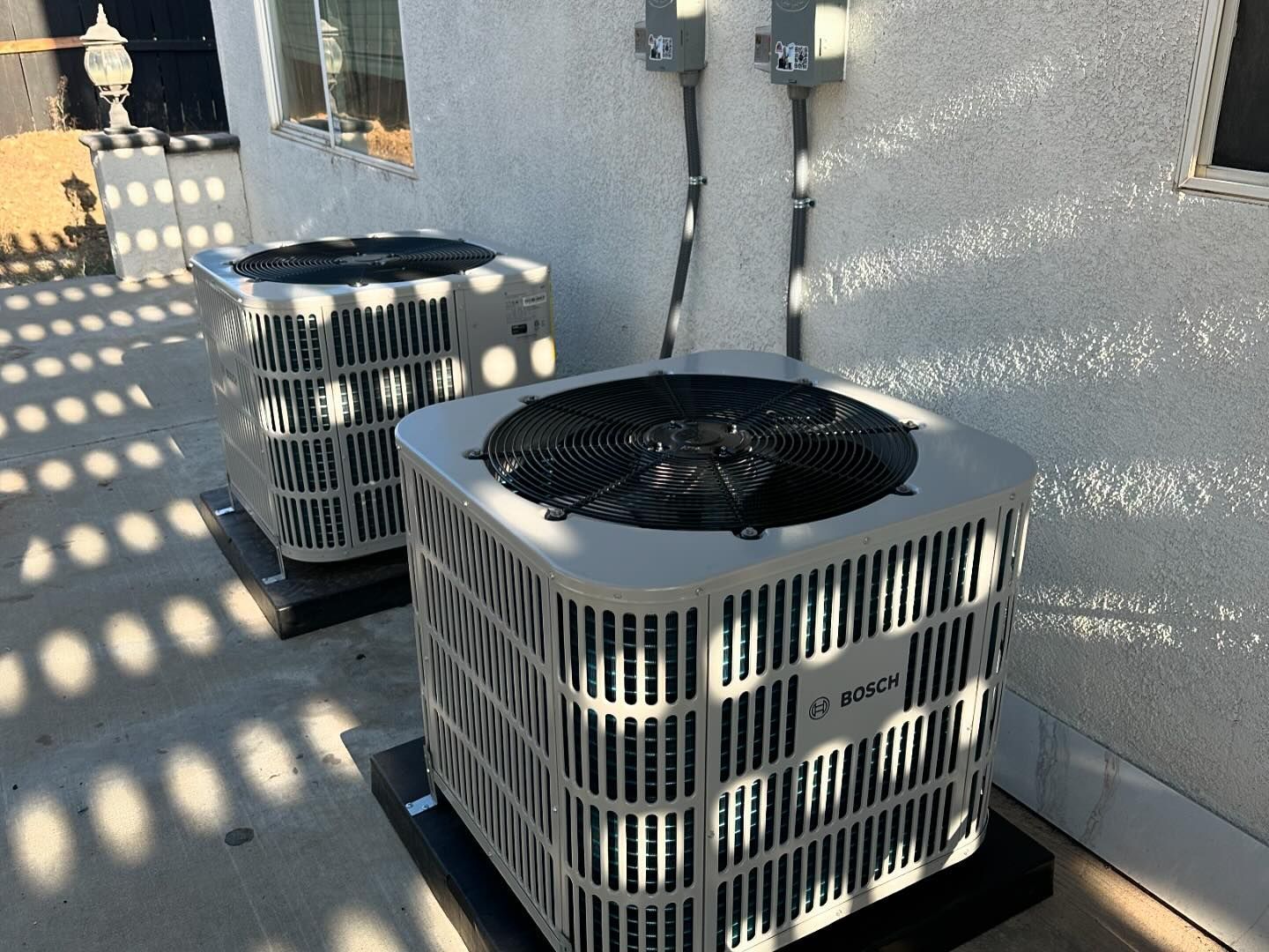 Two air conditioners are sitting on the side of a building.