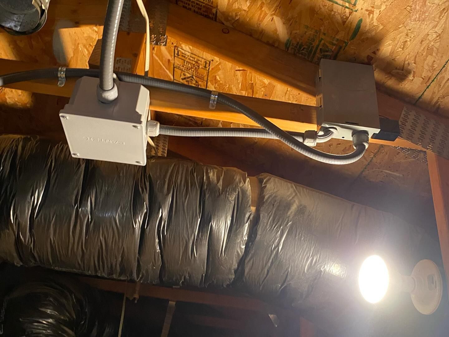 A light is hanging from the ceiling of an attic.