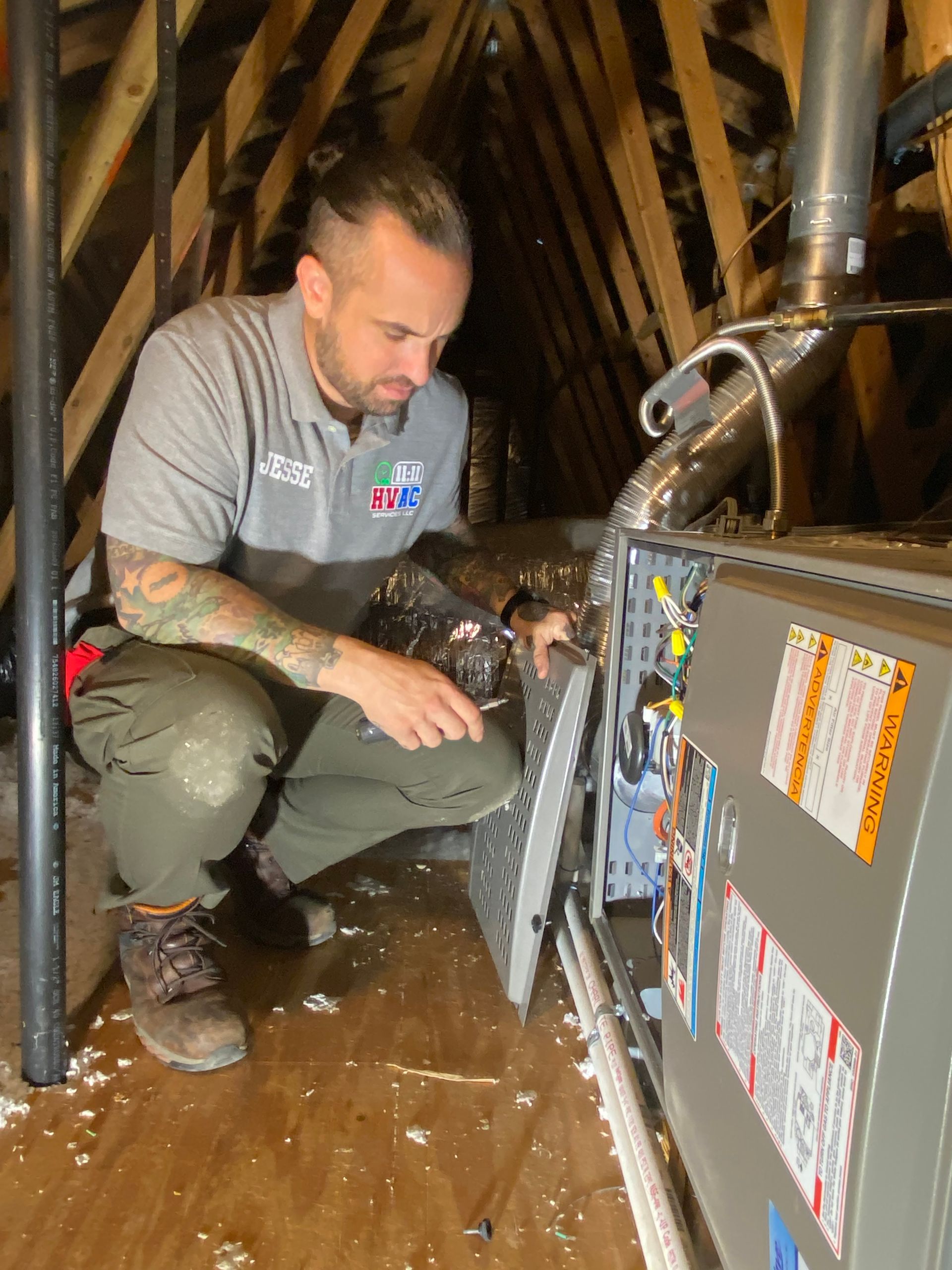 A man is working on an air conditioner in an attic.