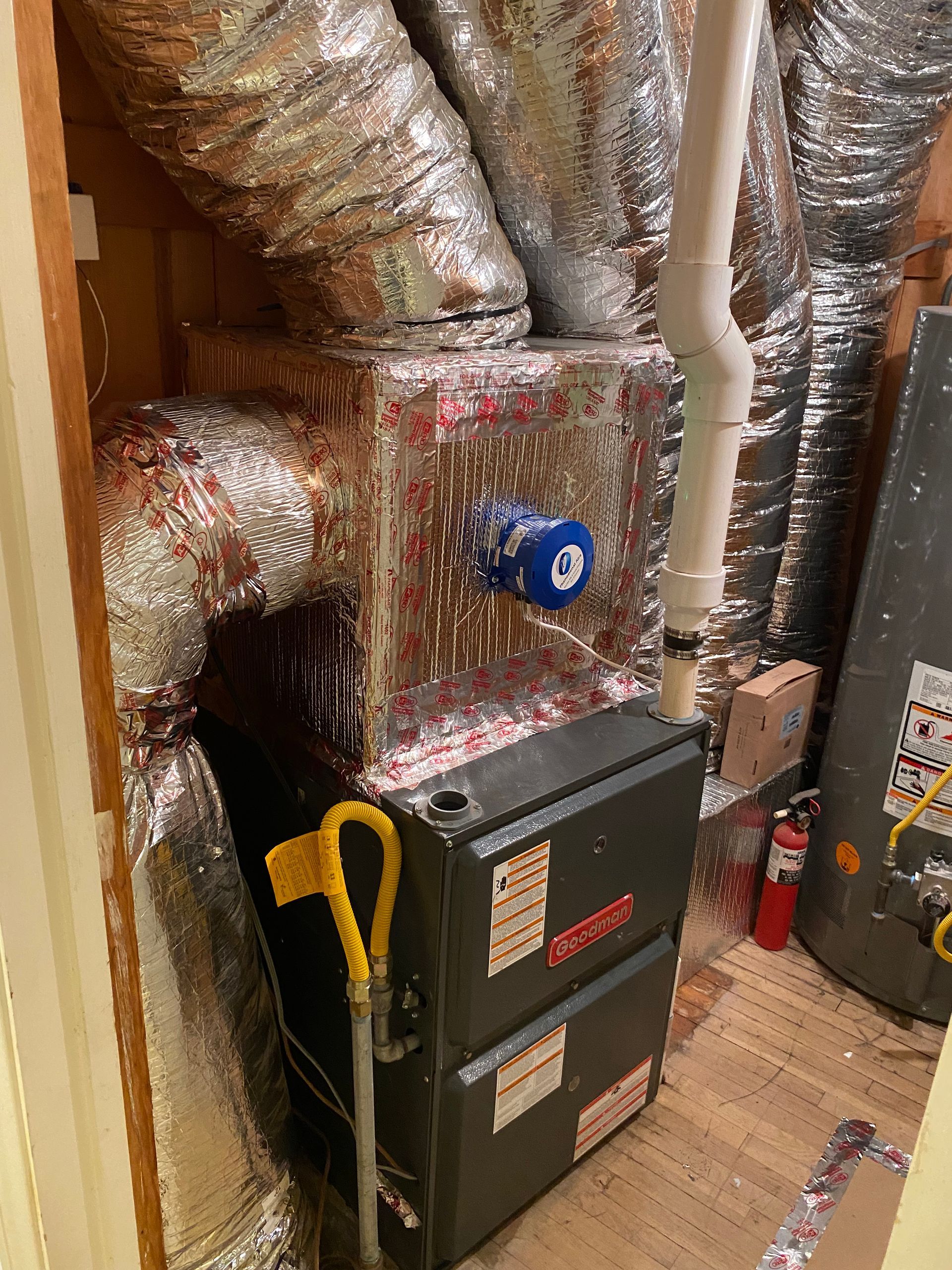 A furnace is sitting in a room with a lot of ducts.