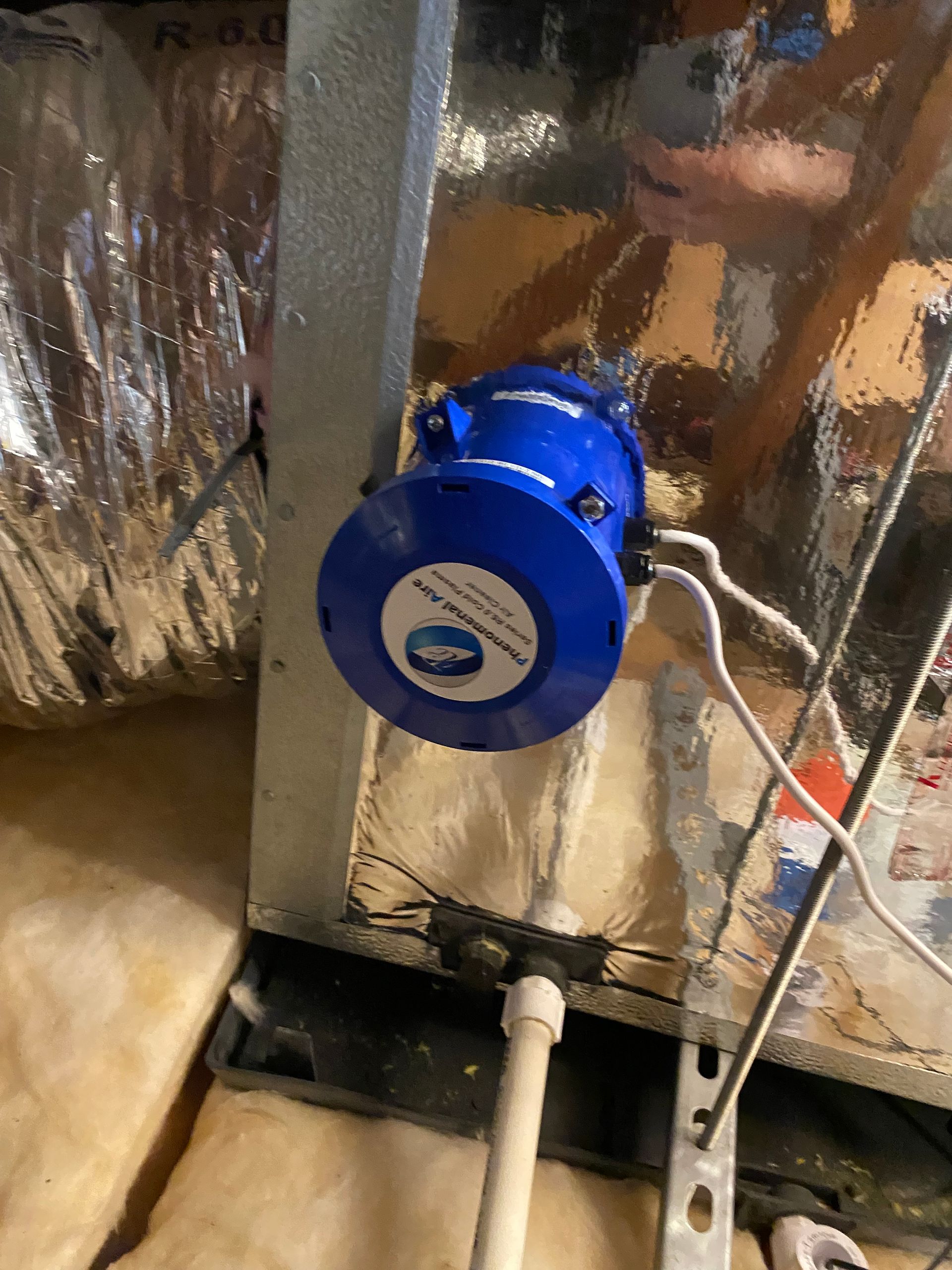 A blue box is sitting next to a pipe in a room.