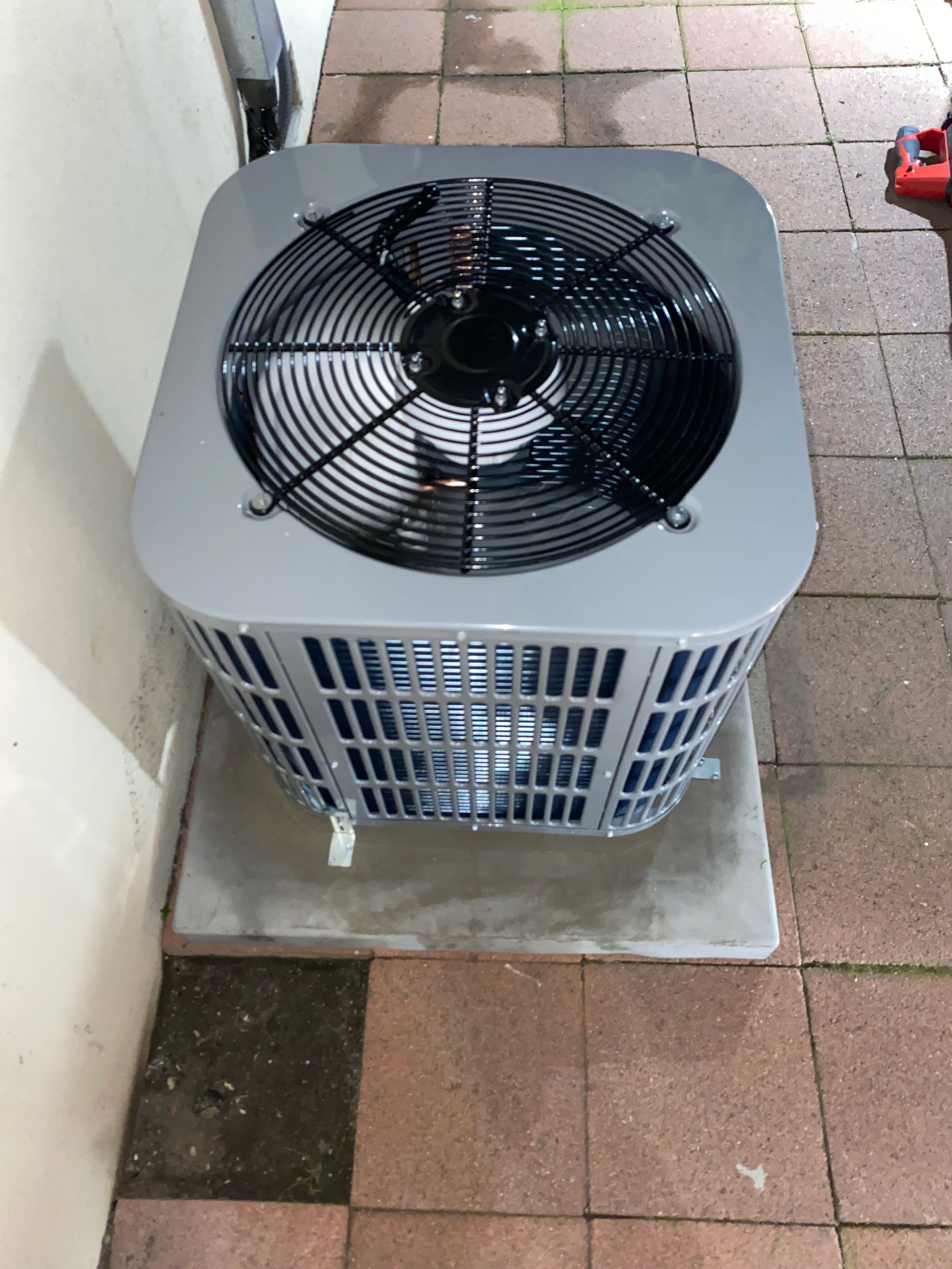 A fan is sitting on a tiled floor next to a wall.