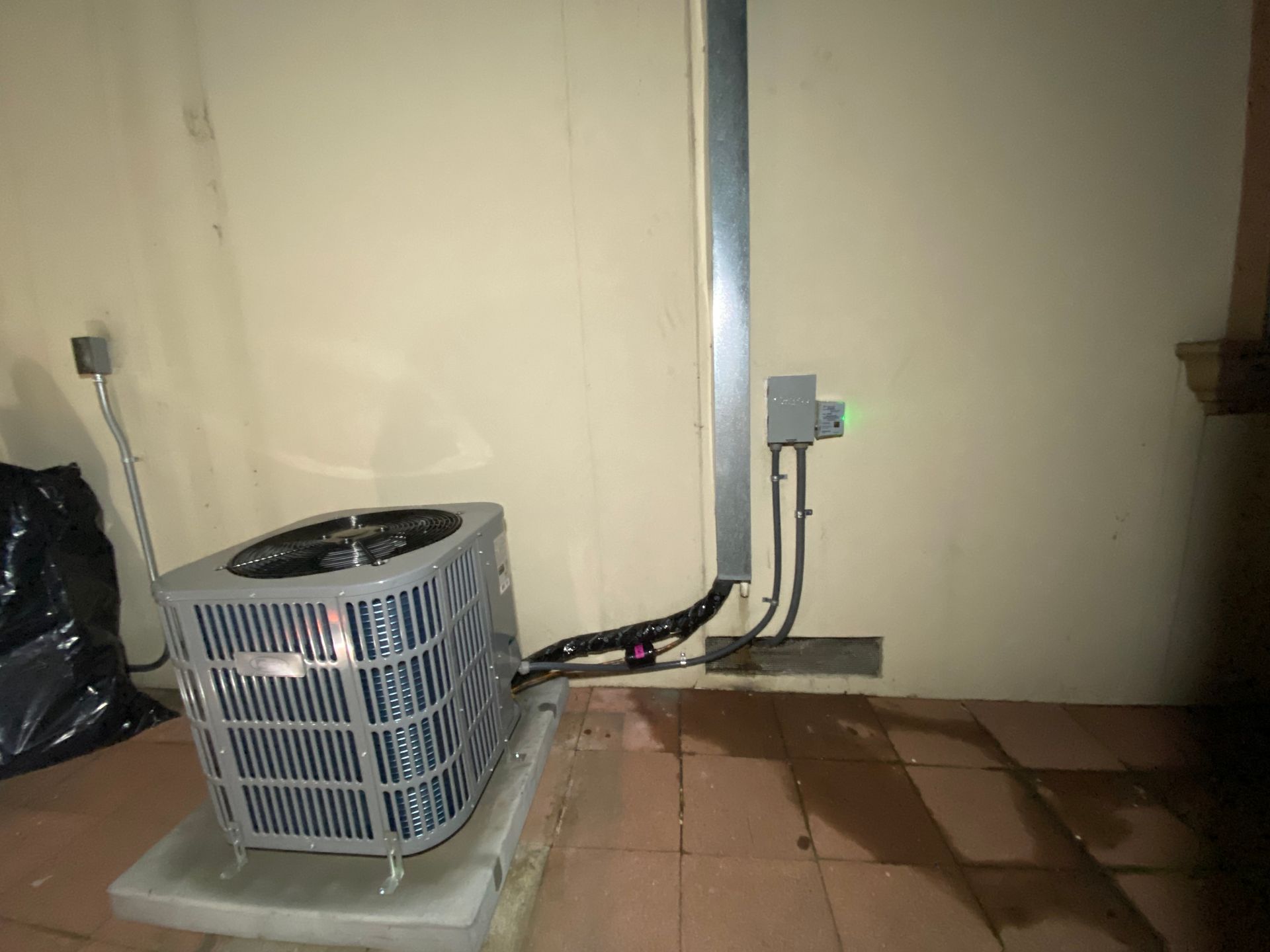 An air conditioner is sitting on a tiled floor next to a wall.
