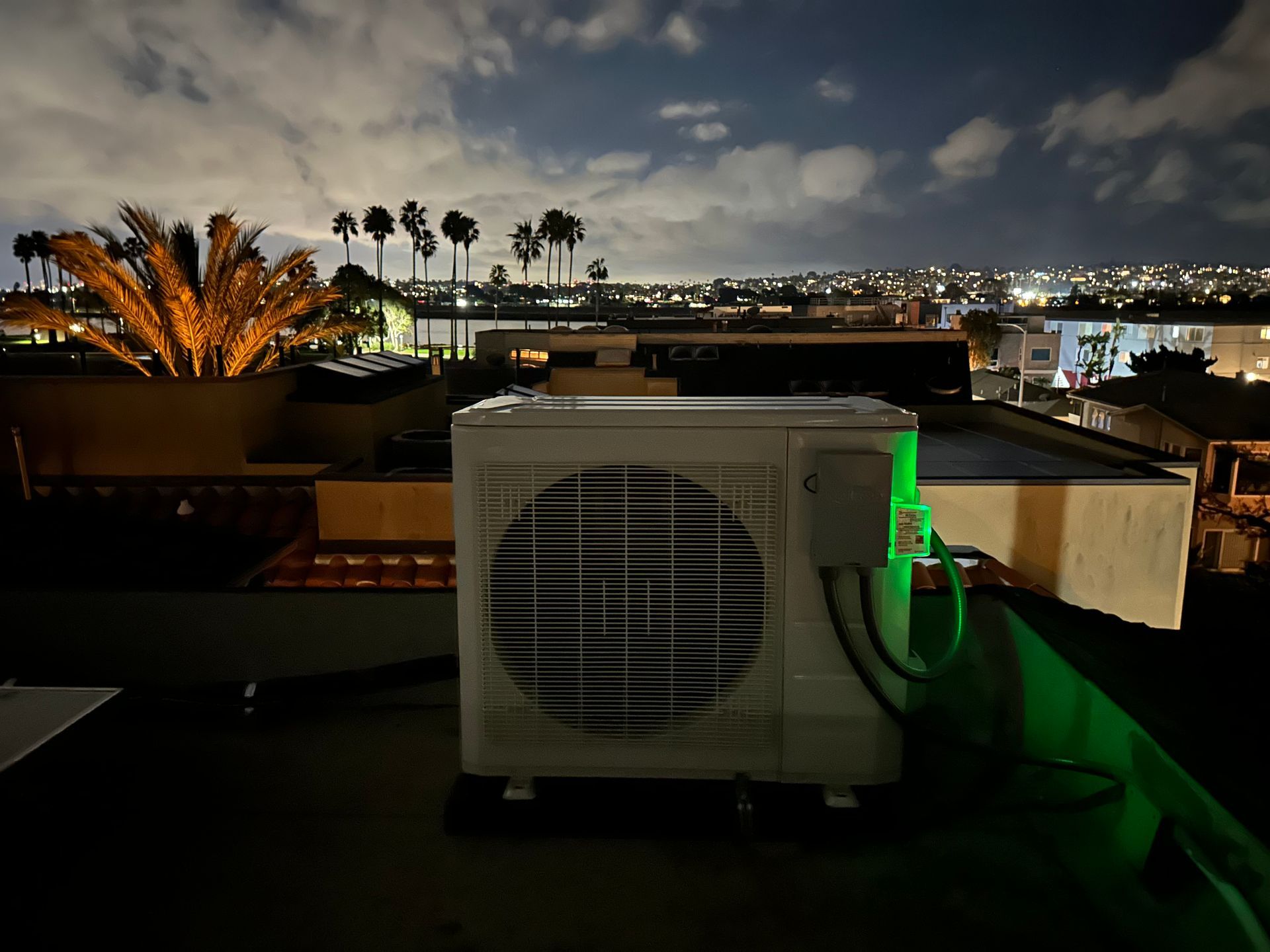An air conditioner is on the roof of a building at night