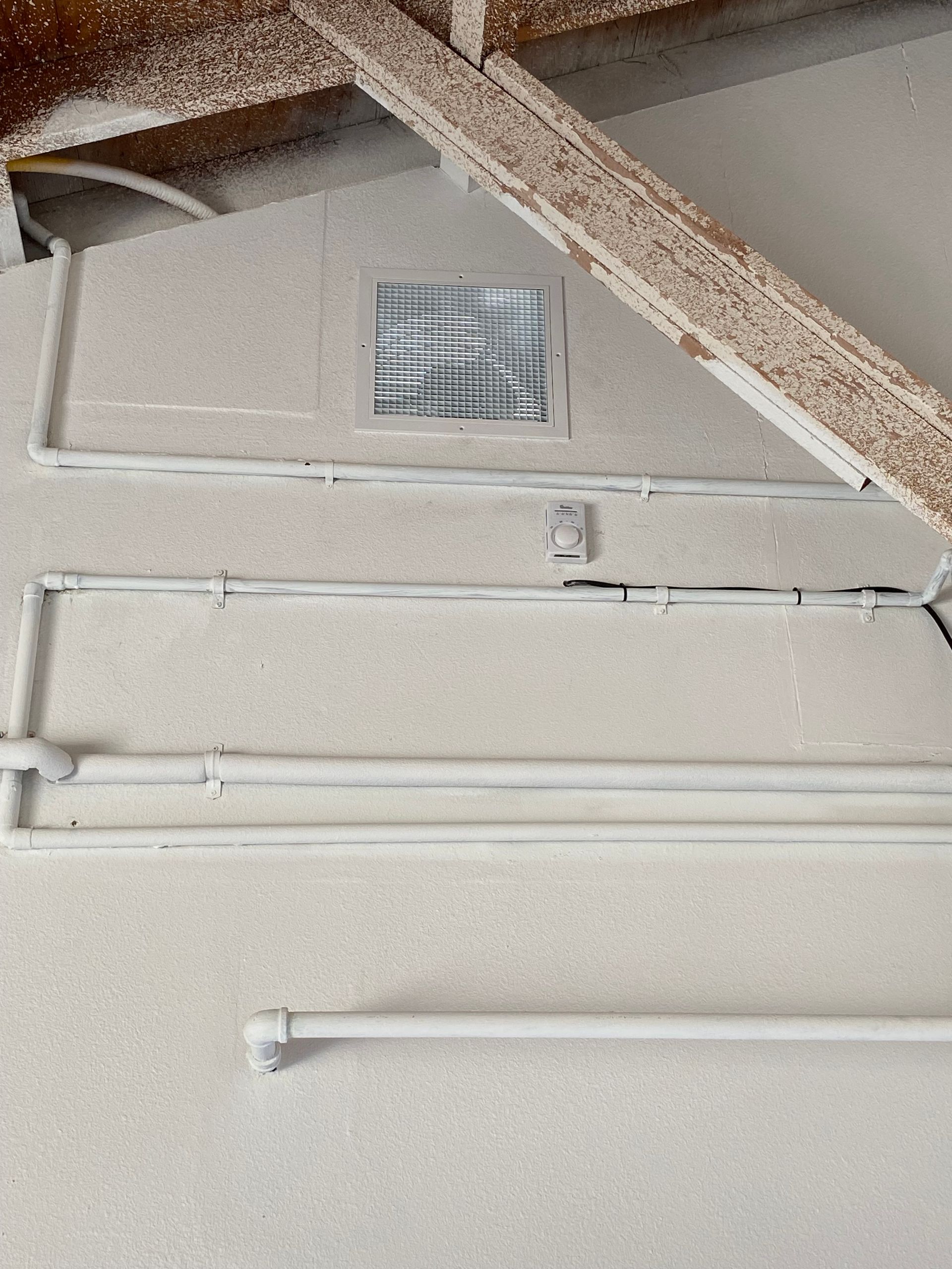 A close up of a wall with pipes and wires on it