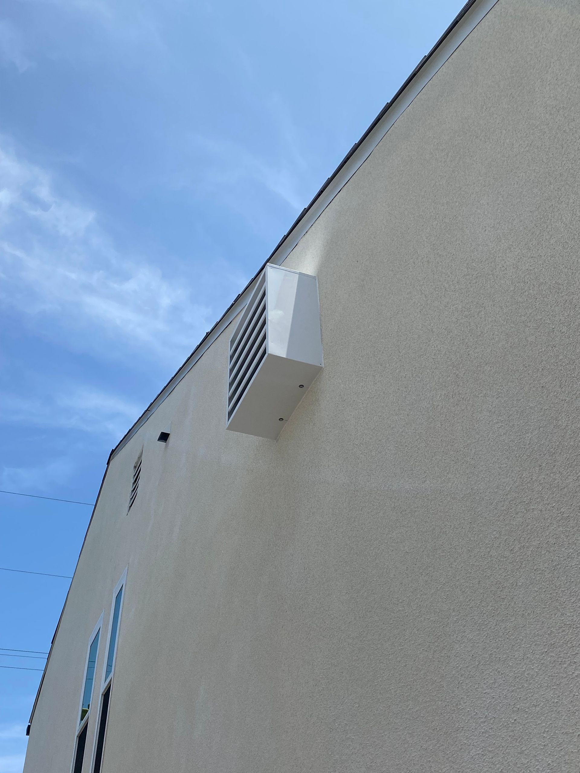 A white building with a fan on the side of it