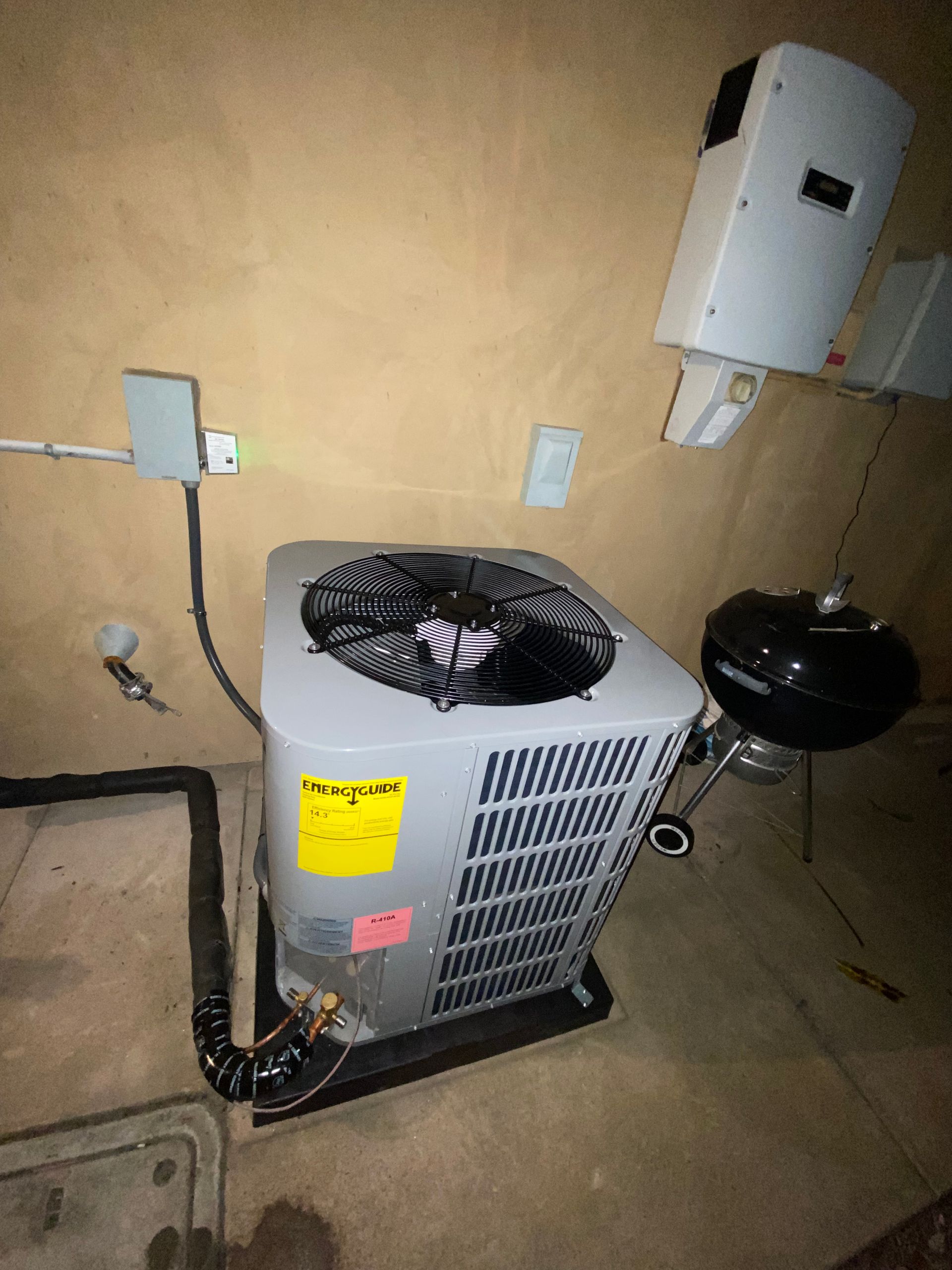 An air conditioner is sitting in a room next to a grill.