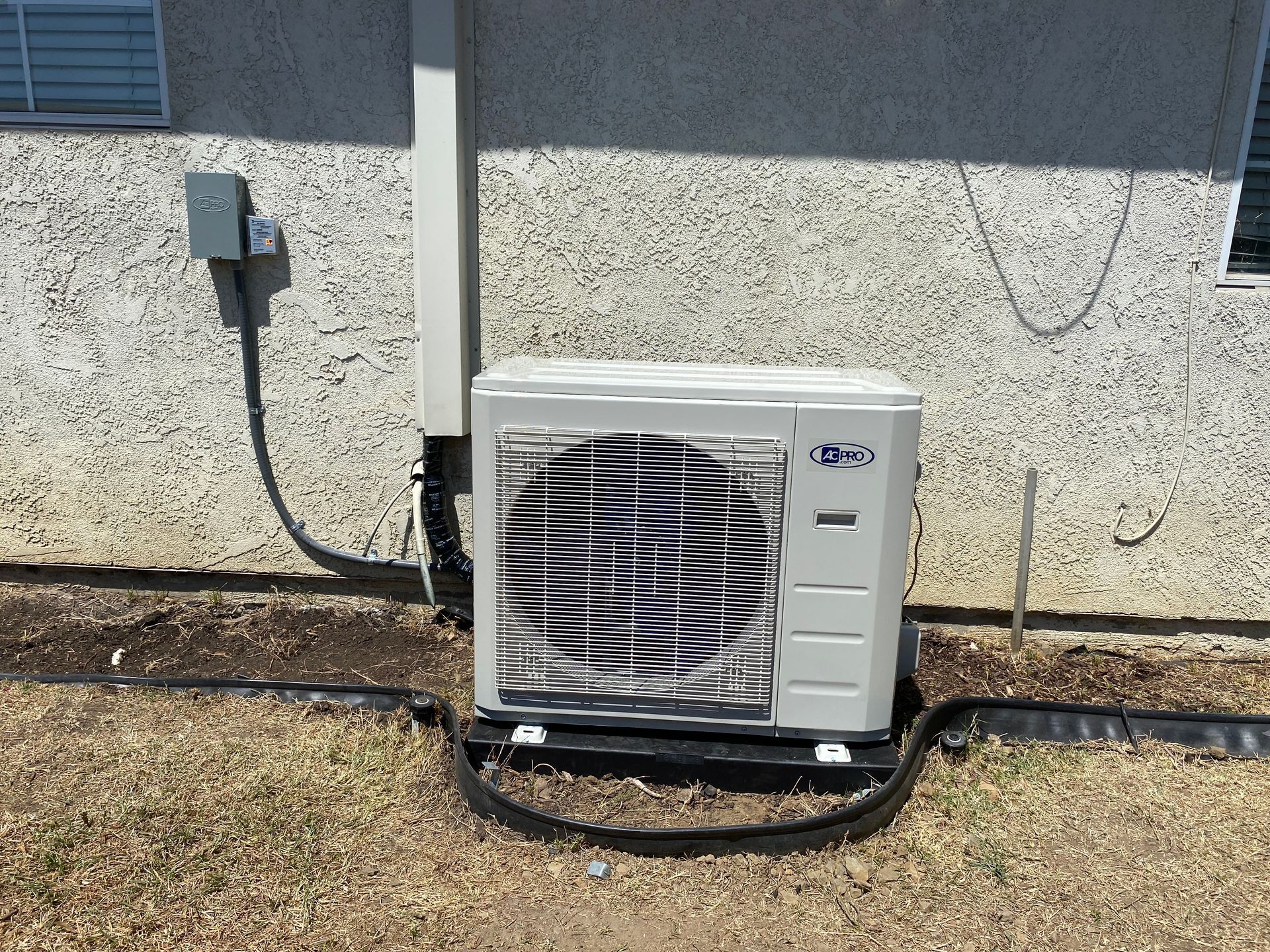 A white air conditioner is sitting on the side of a building.