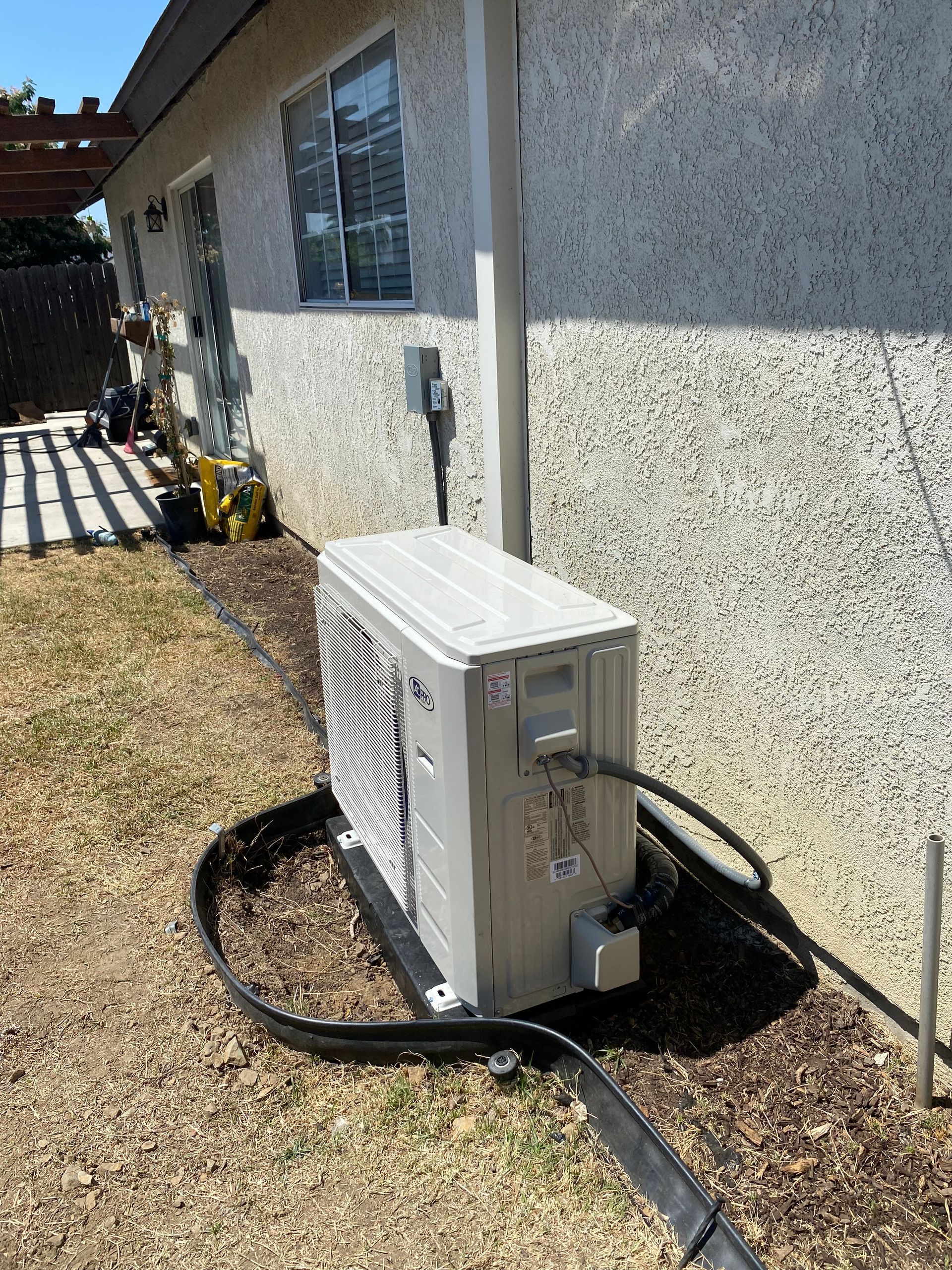 A white air conditioner is sitting on the side of a house.