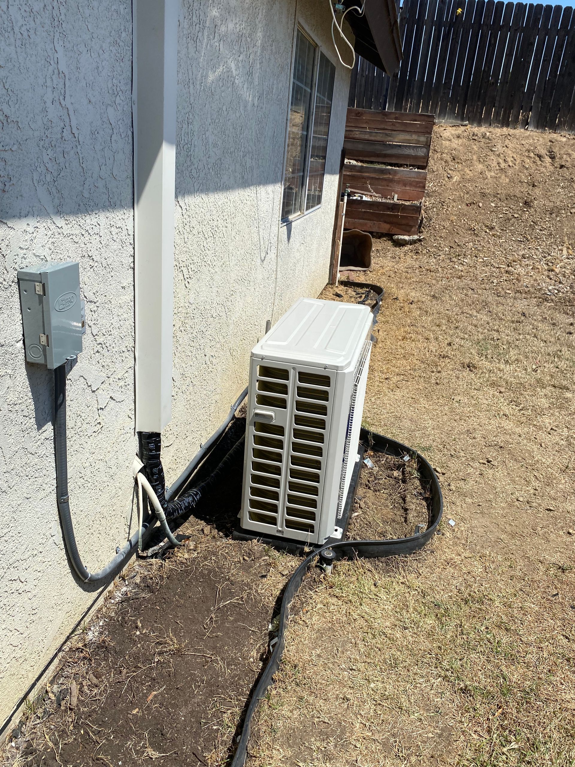An air conditioner is attached to the side of a house.