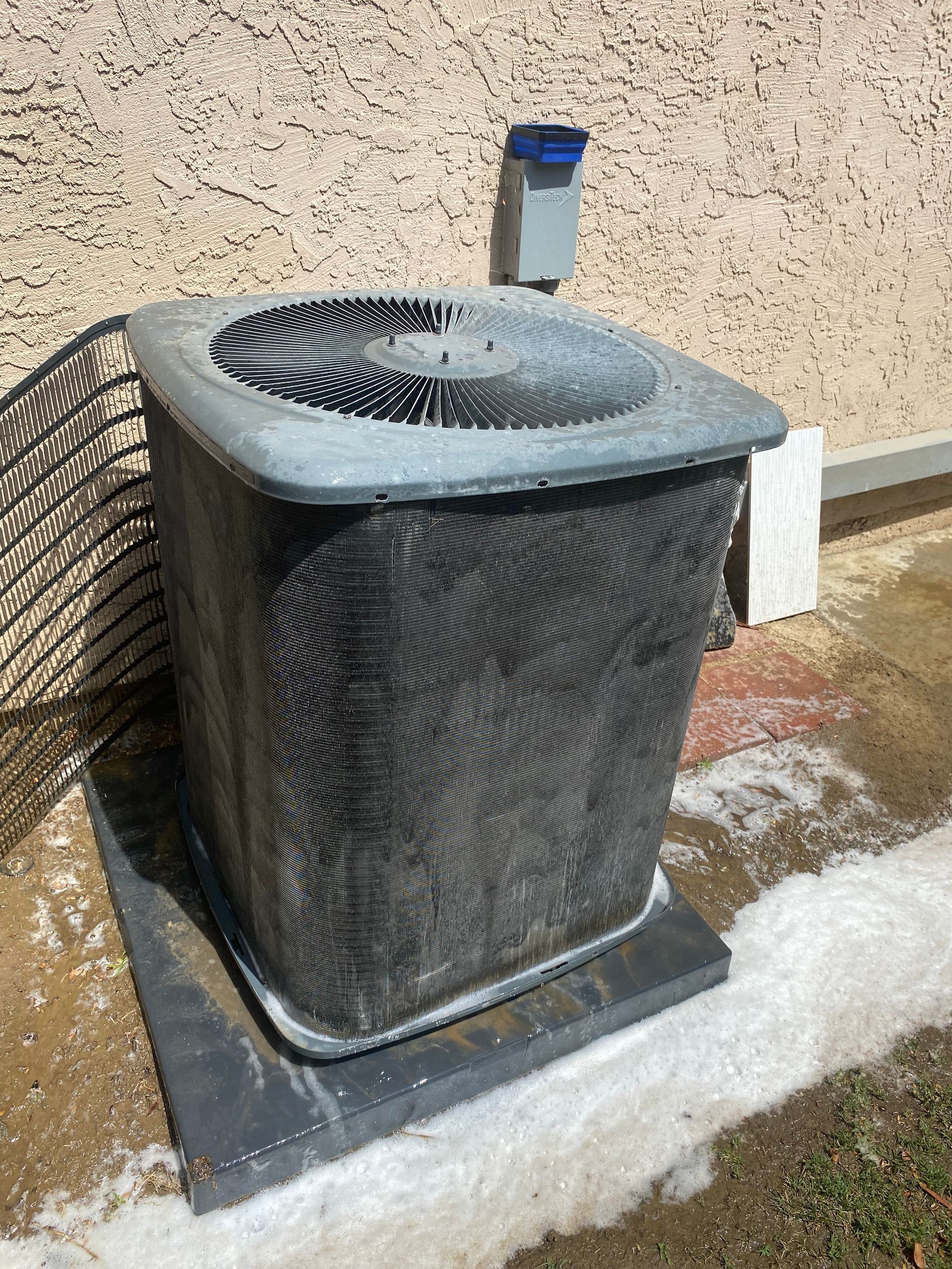 A dirty air conditioner is sitting on the side of a building.