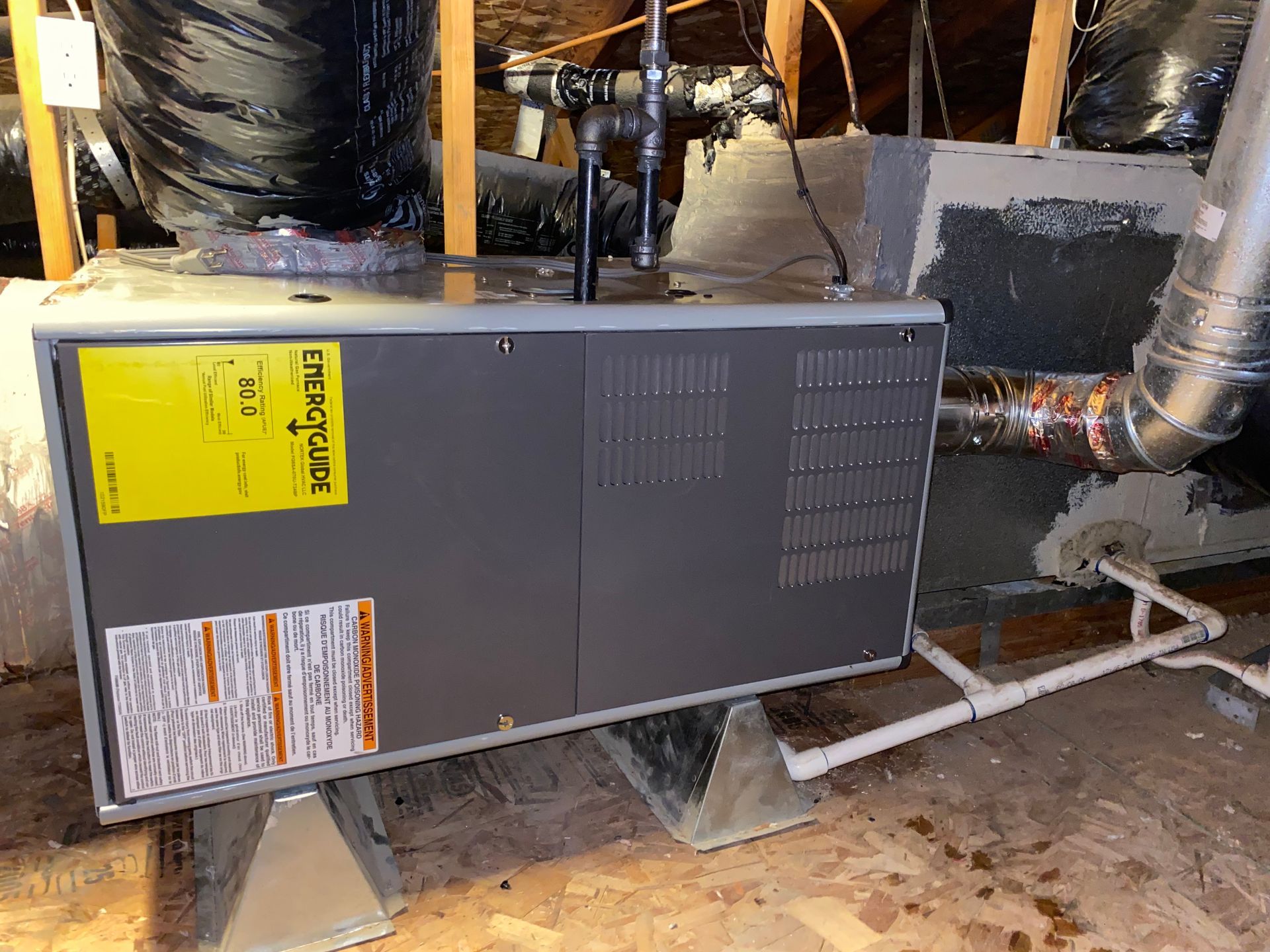 A gas furnace is sitting in the attic of a house.