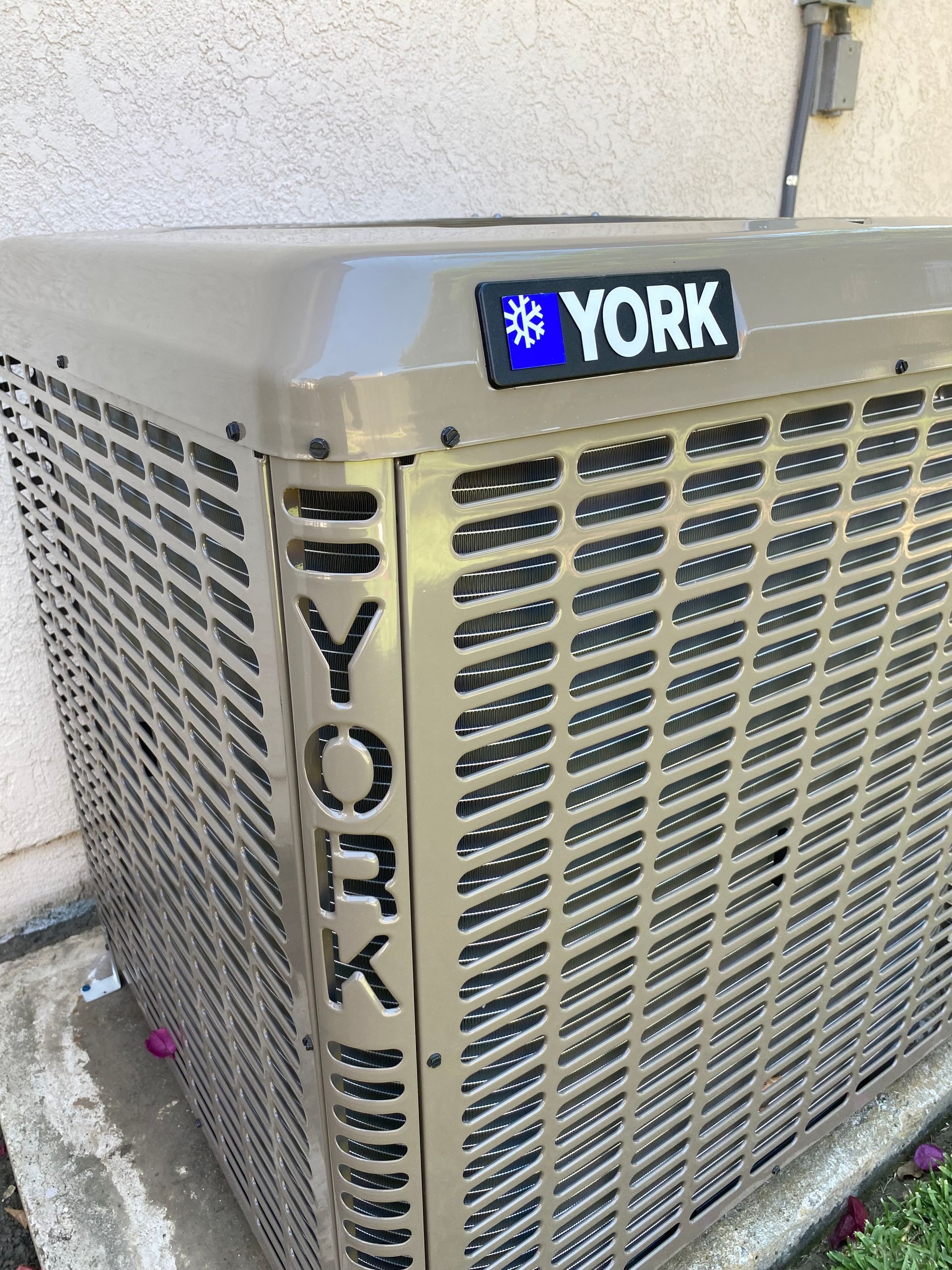 A york air conditioner is sitting outside of a building.