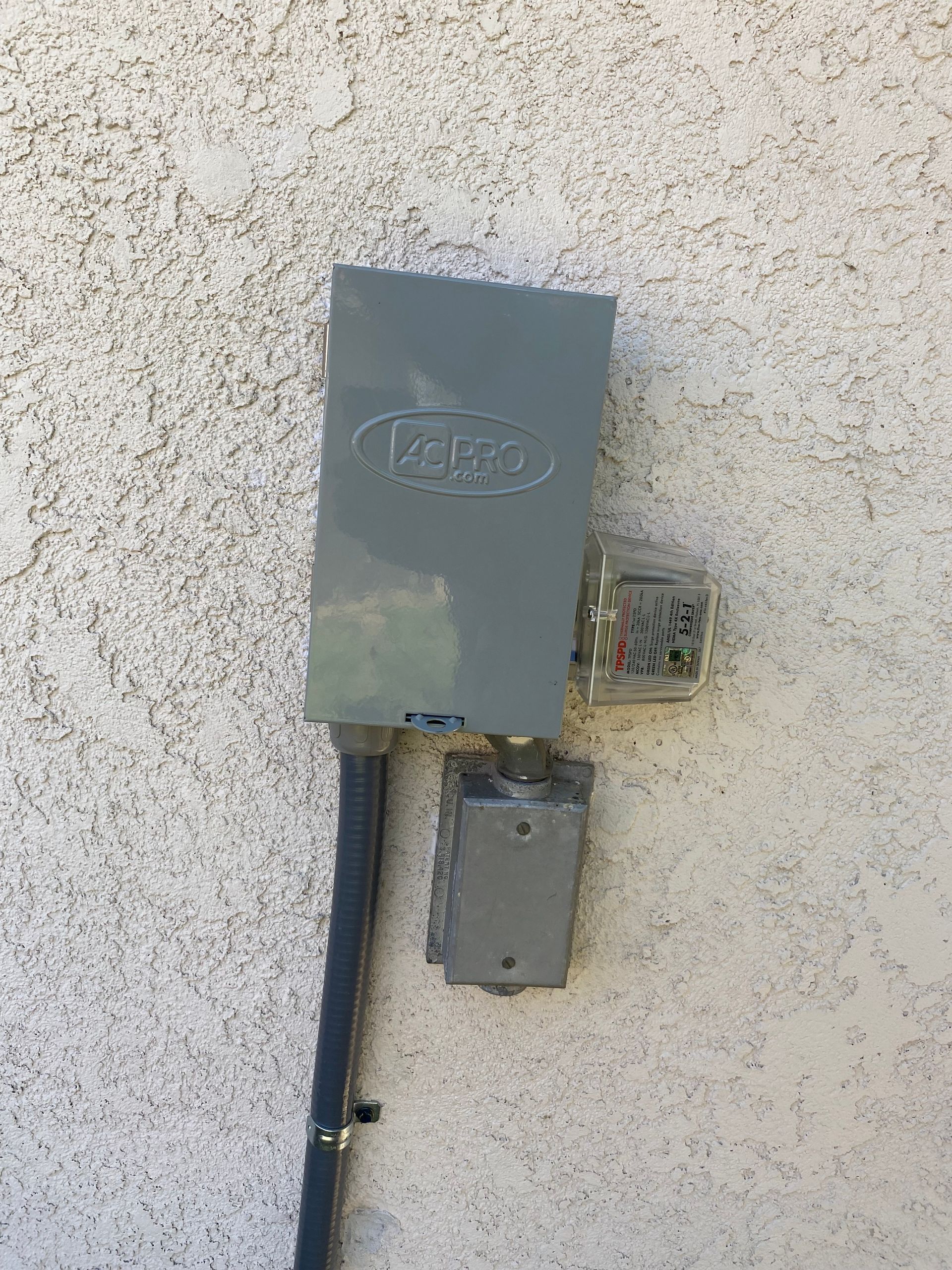 A gray box is attached to a white wall.