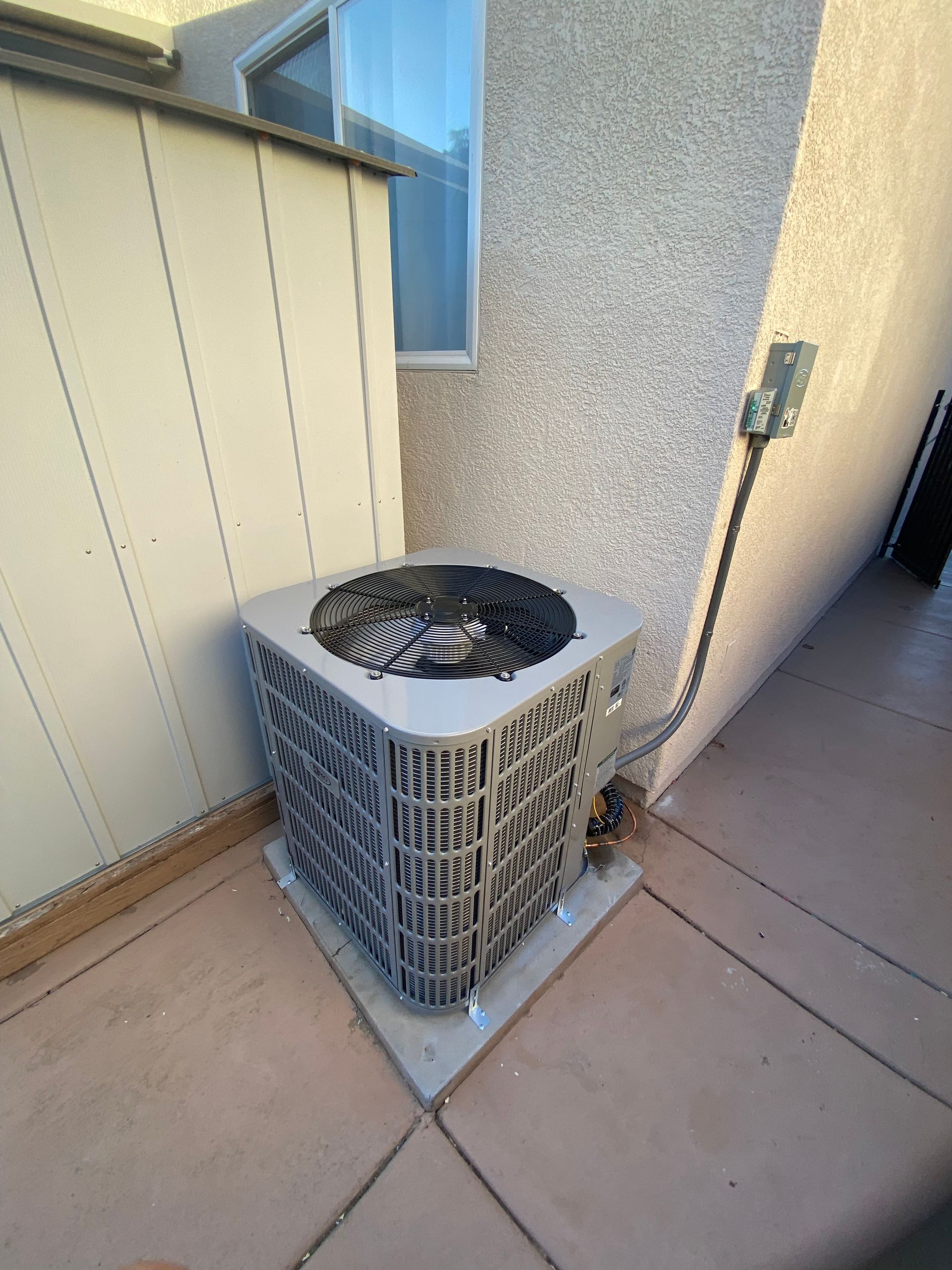 An air conditioner is sitting on the side of a building next to a window.