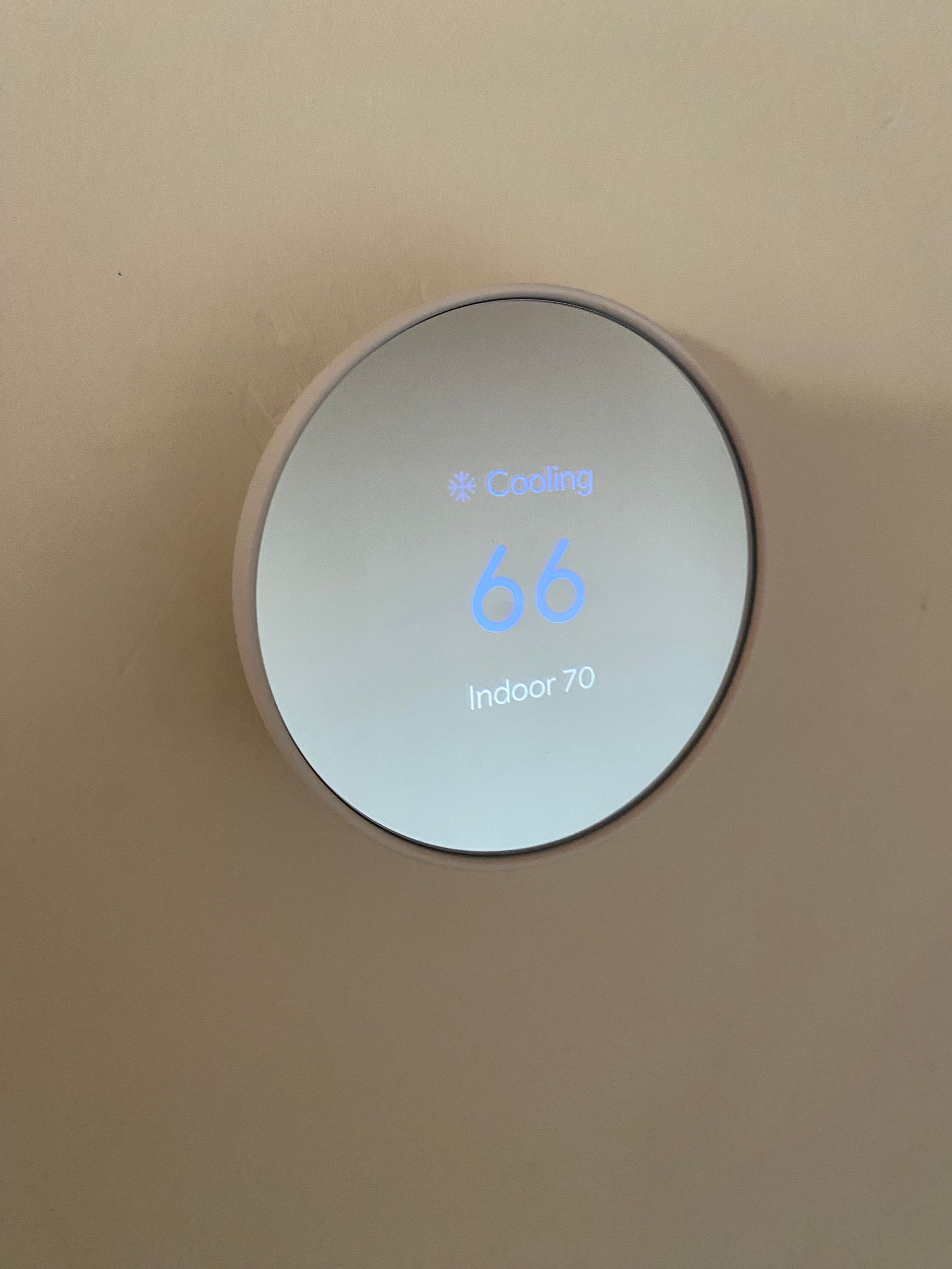 A close up of a thermostat that says 66 degrees