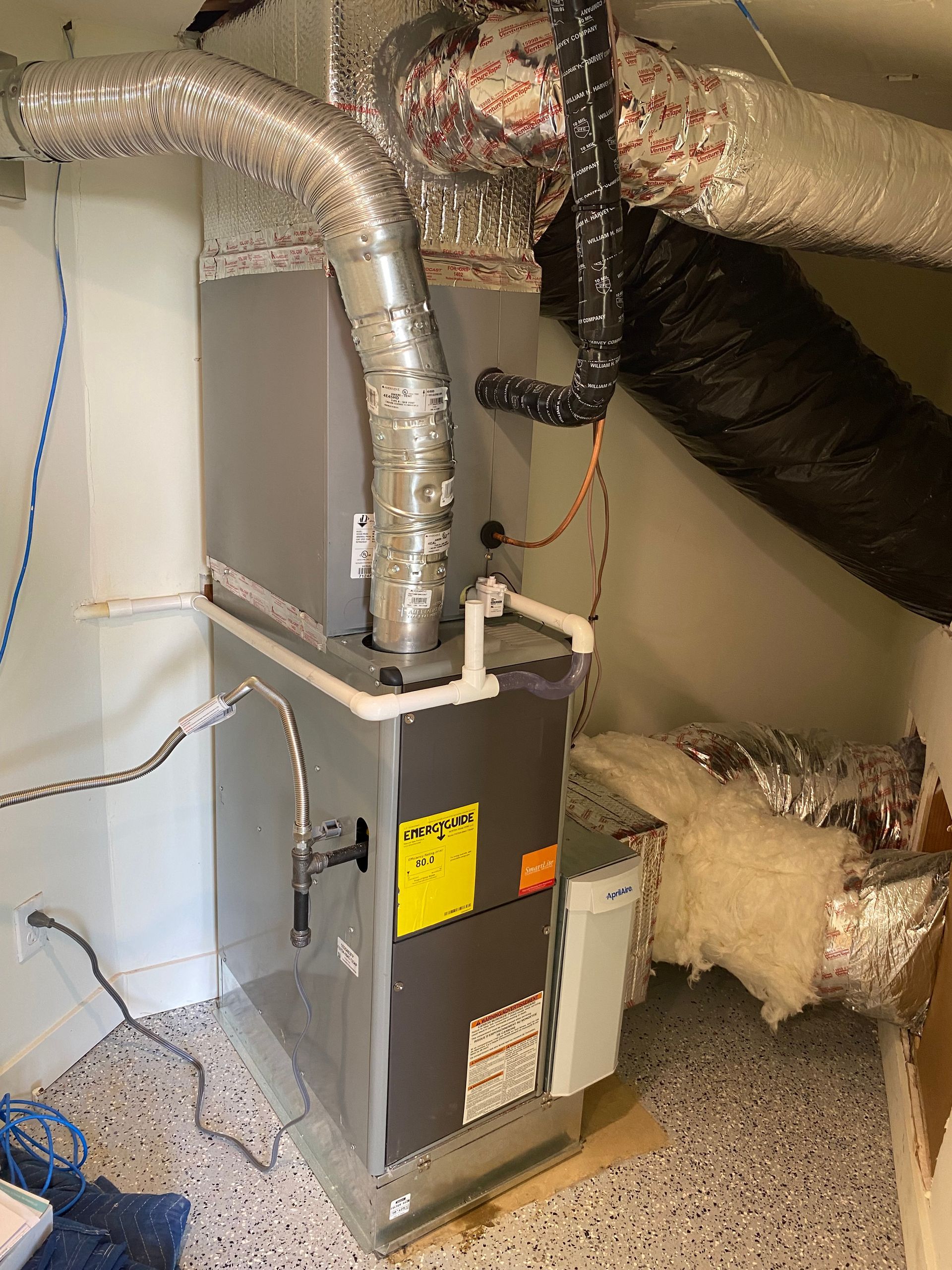 A furnace is sitting in a corner of a room.