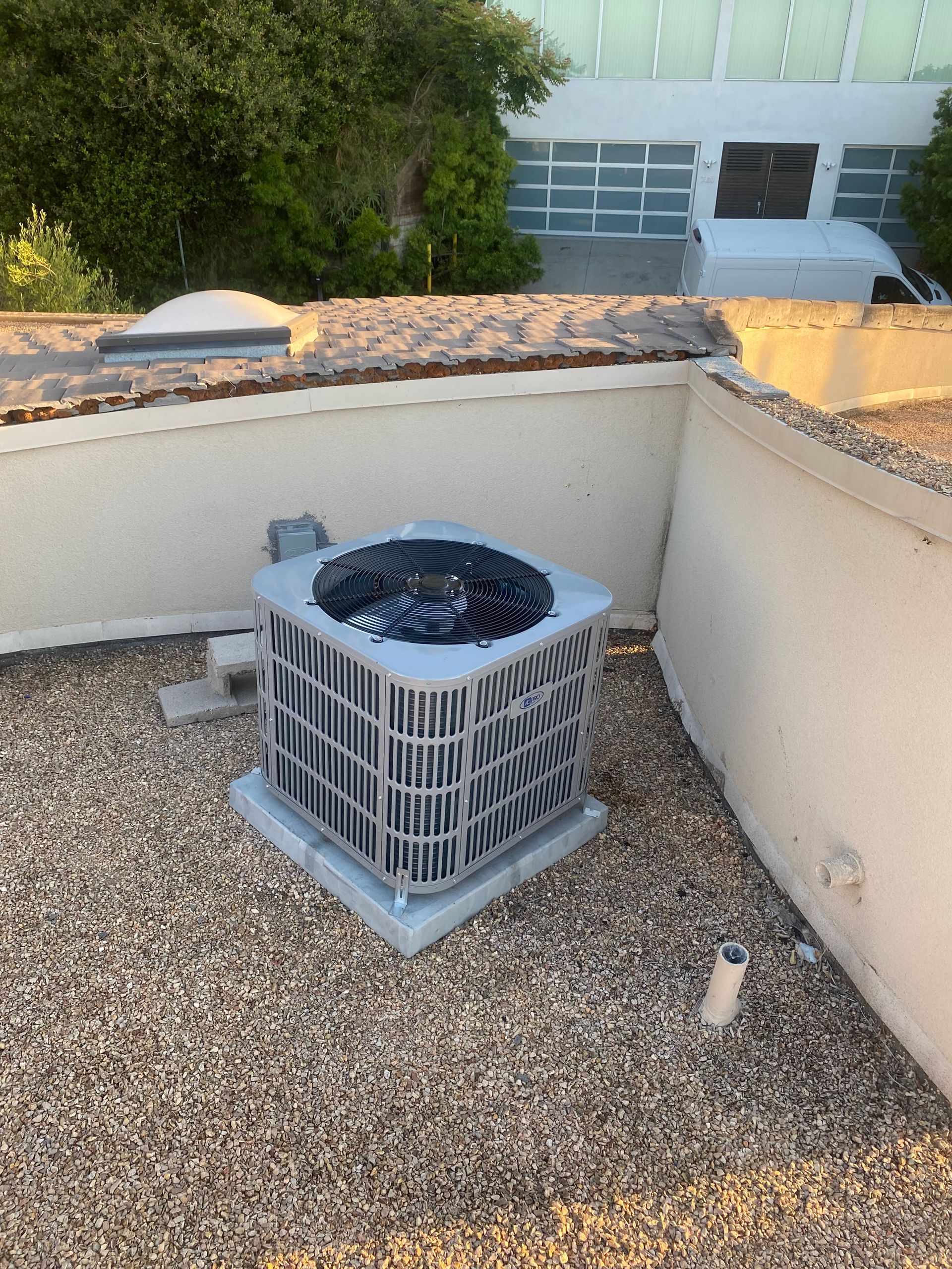 An air conditioner is sitting on top of a gravel roof.
