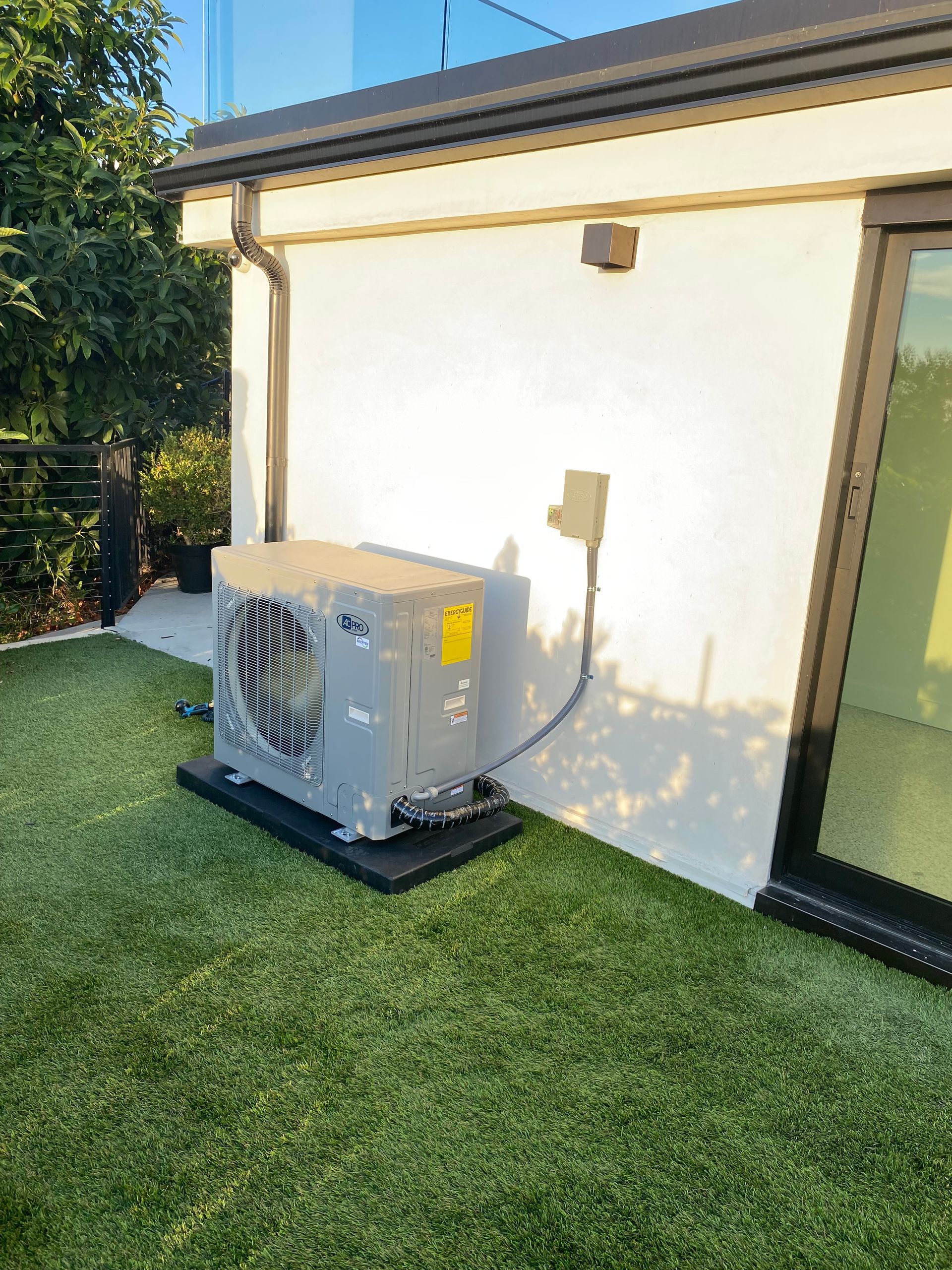 An air conditioner is sitting on top of a lush green lawn in front of a house.