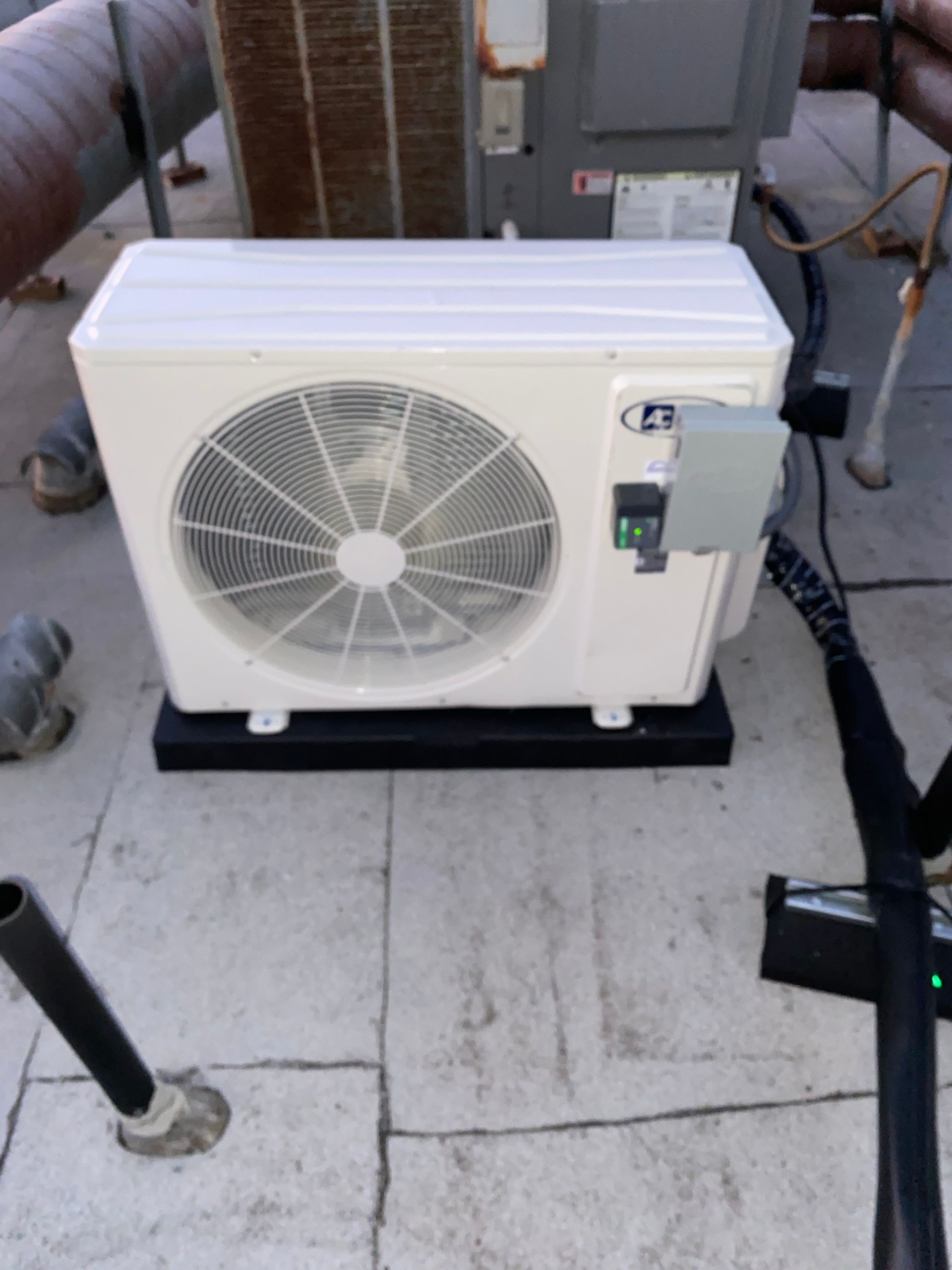 A white air conditioner is sitting on a tiled floor