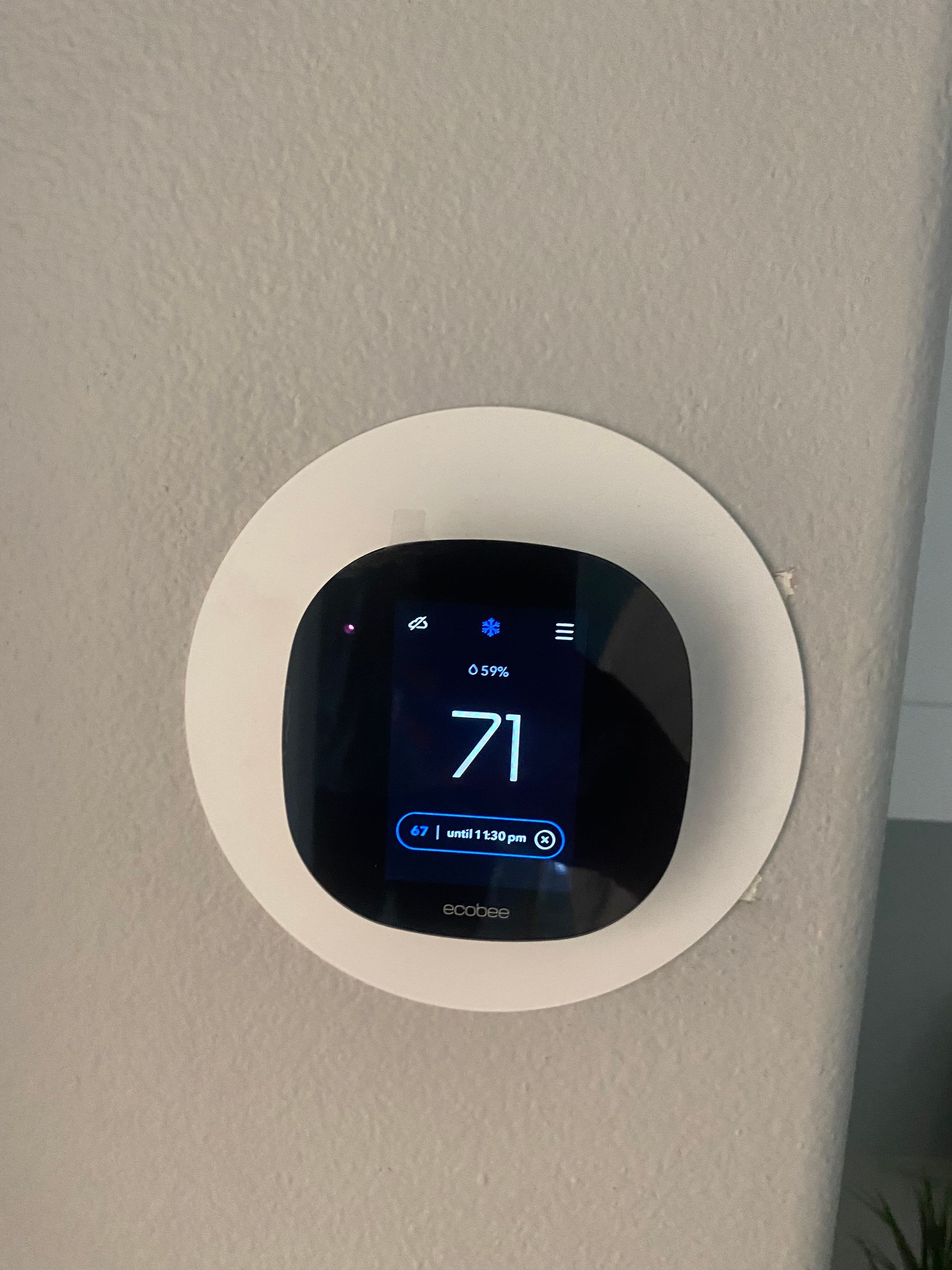 A thermostat is mounted on a wall and shows the temperature as 71 degrees fahrenheit.