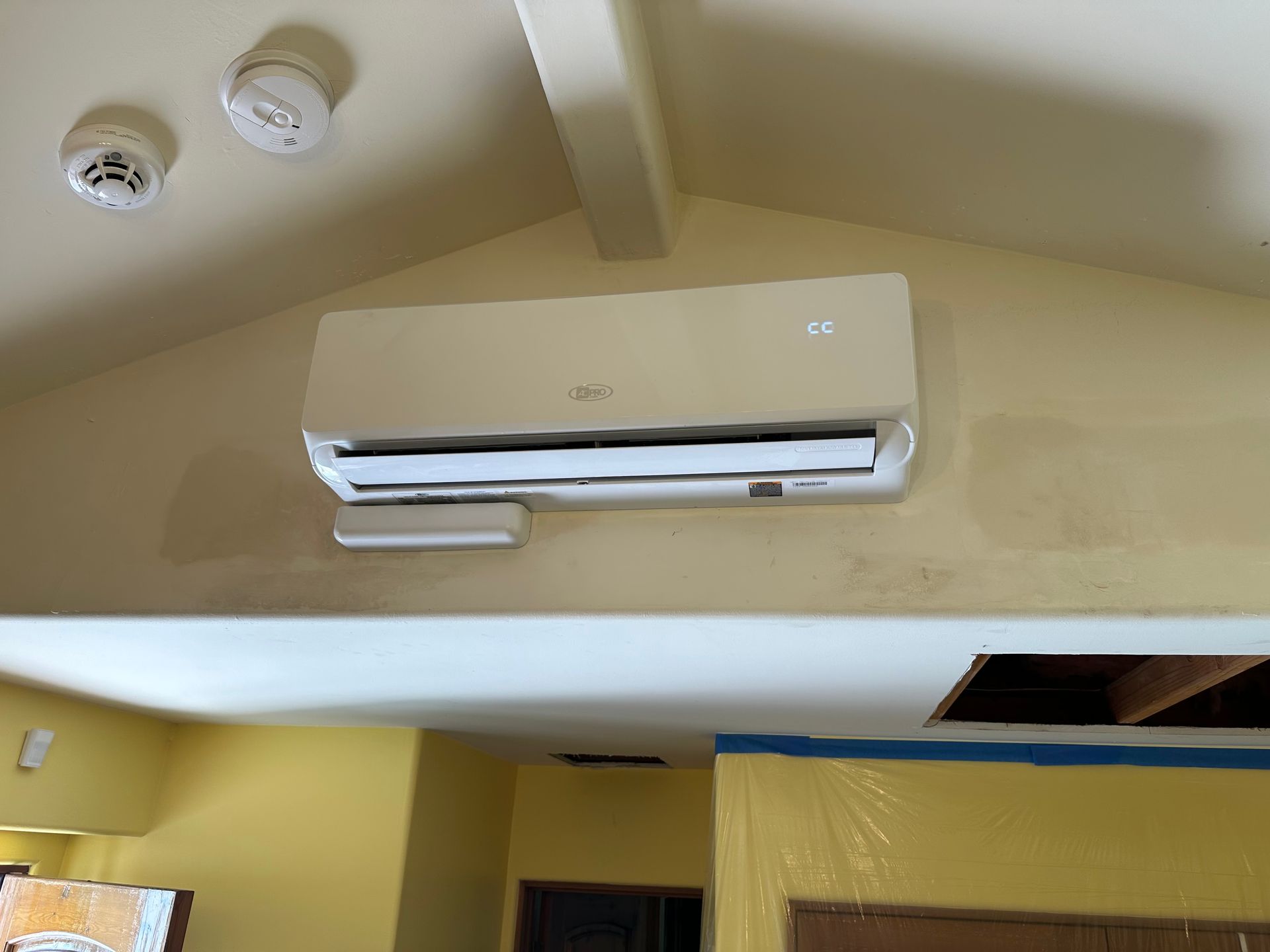 A white air conditioner is hanging from the ceiling in a room.