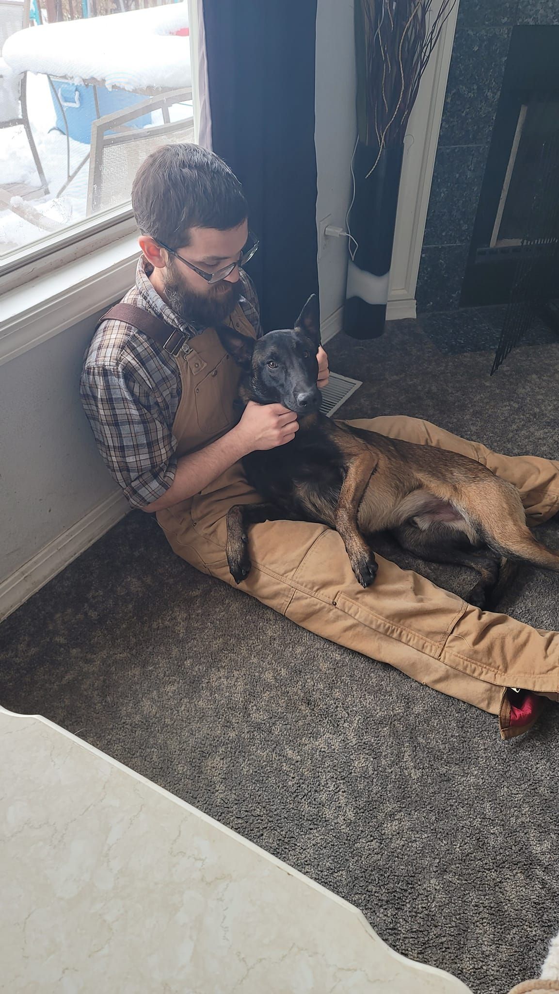 A man is sitting on the floor holding a dog.