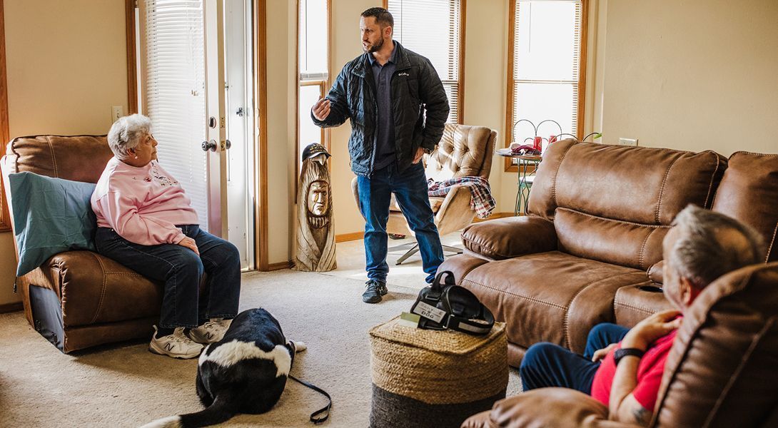 A man is kneeling down next to a german shepherd dog.