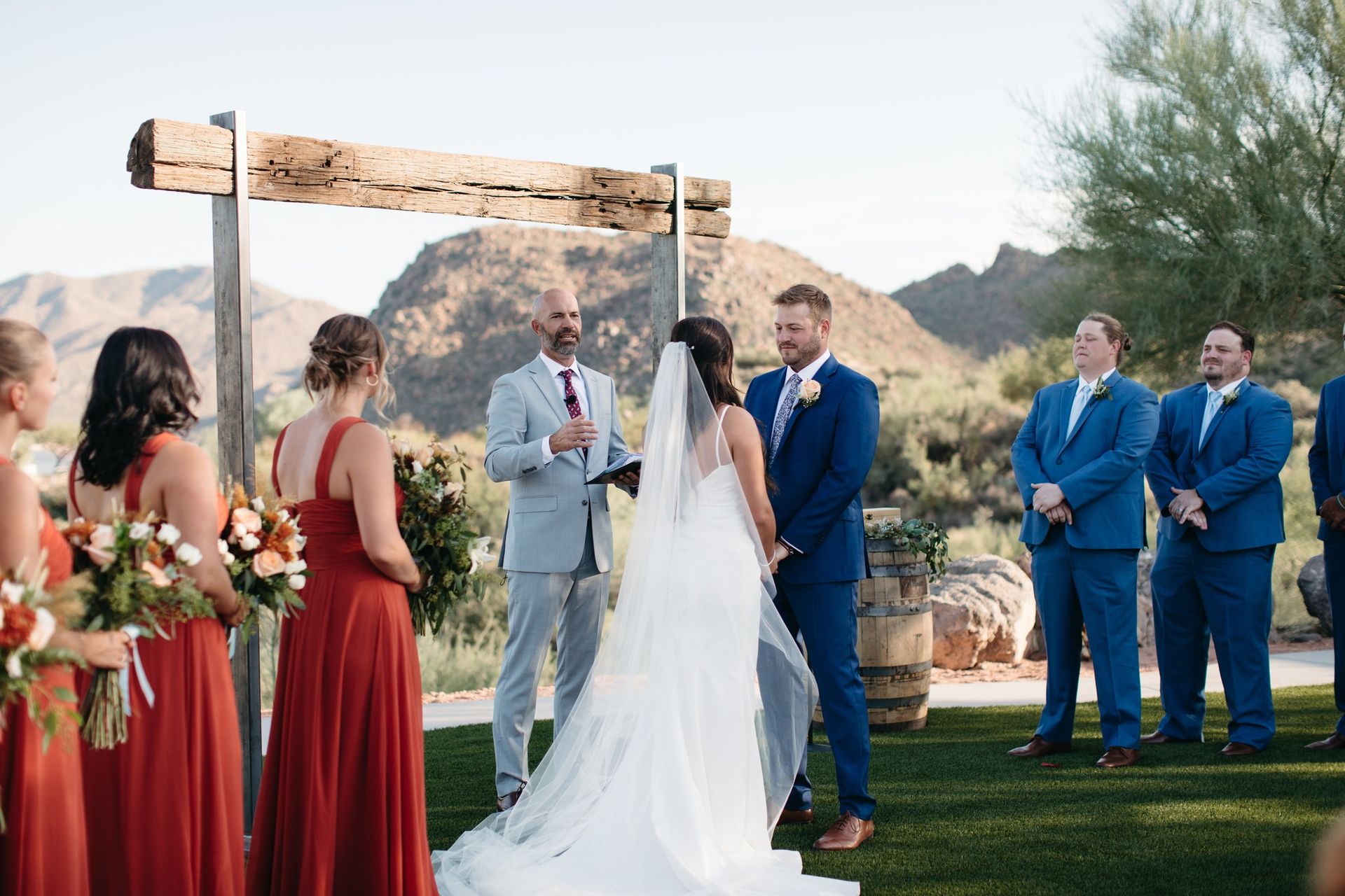 Bride and groom standing at alter with officiant with wedding parties standing by at Venue at the Cove