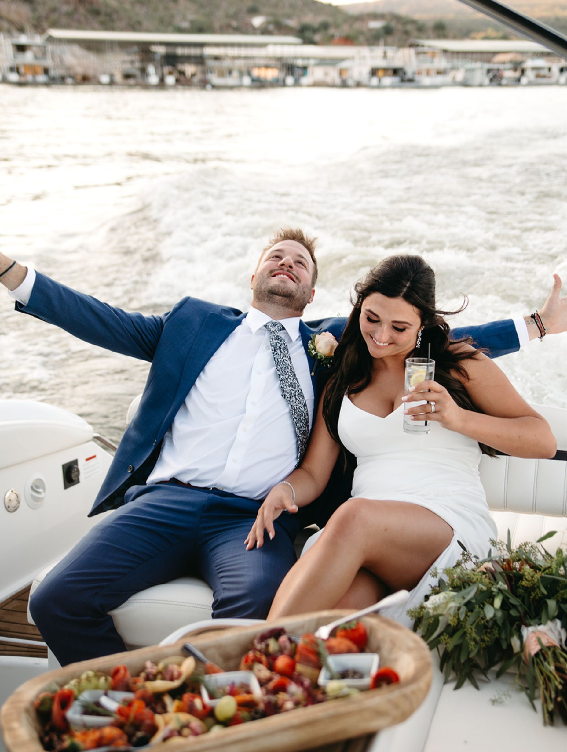 Bride and groom with drinks and charcuterie board on boat ride part of the Yellow Cliffs Wedding Package from Venue at the Cove