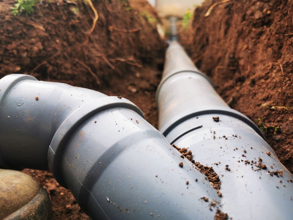 A couple of pipes are laying in the dirt in a trench.