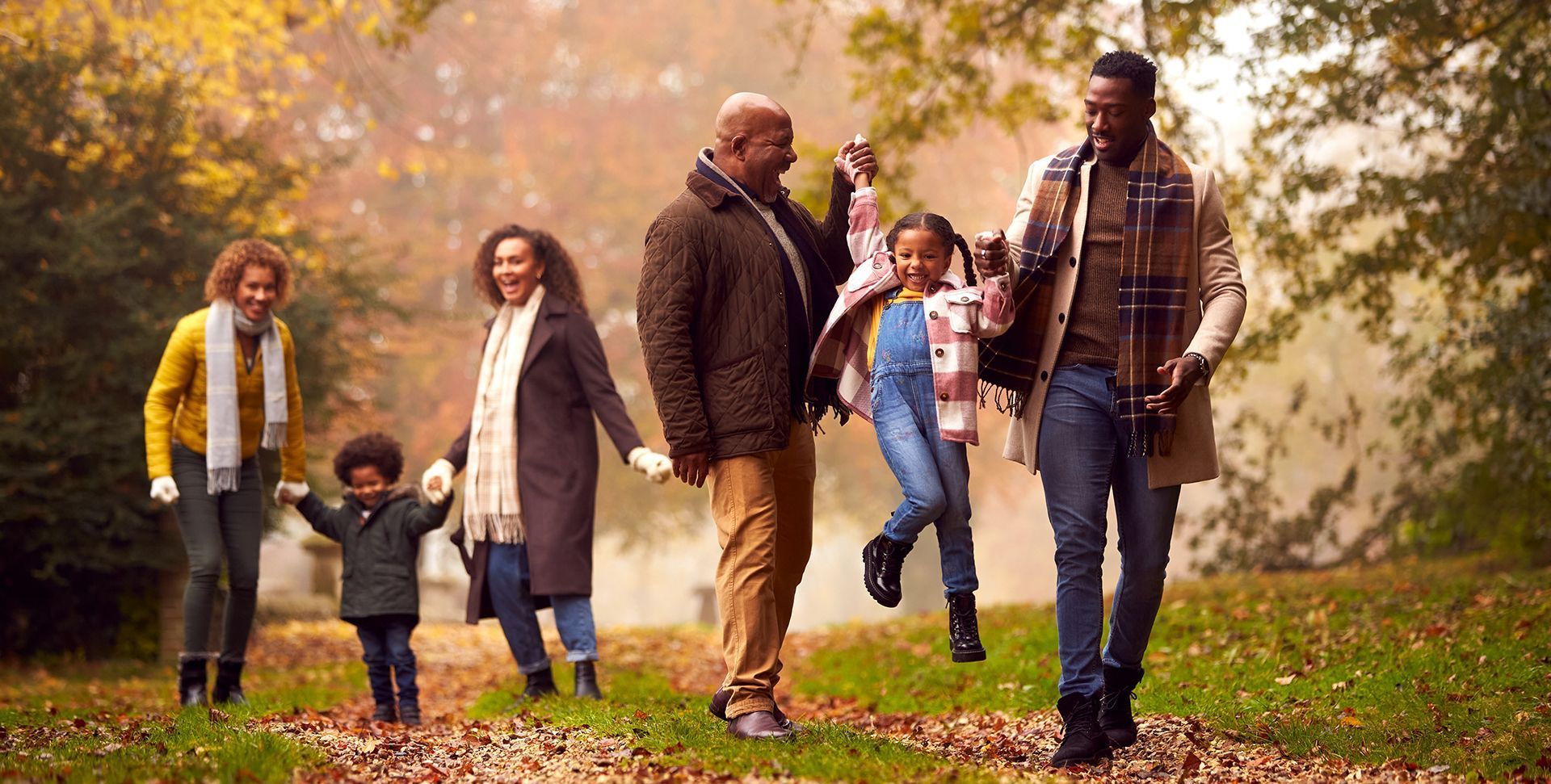 an elderly couple is sitting in the leaves under a tree .