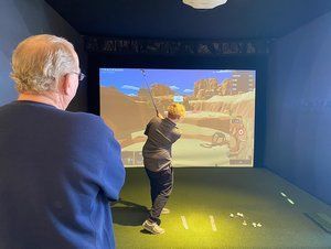 A man is playing a video game of golf in a simulator.