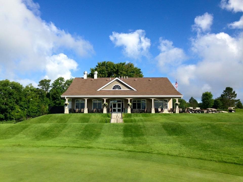 A large house is sitting on top of a lush green hill.