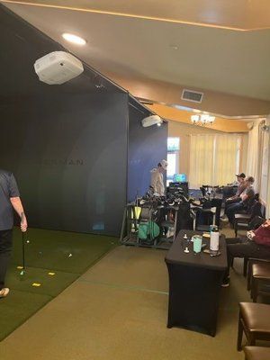 A man is holding a golf club in a golf simulator.