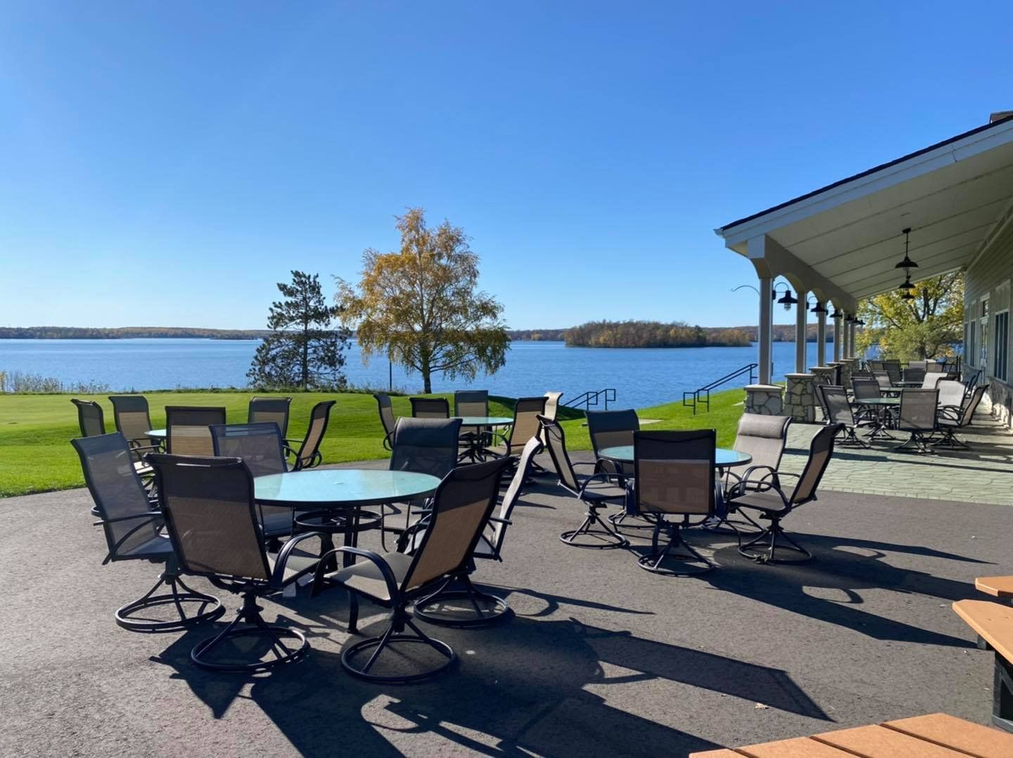 A patio with tables and chairs overlooking a lake