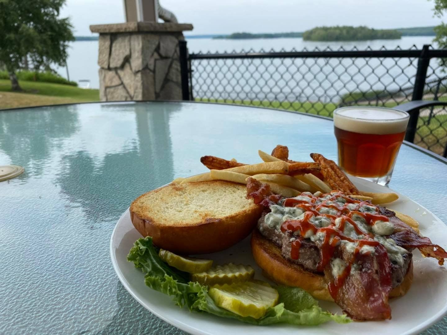 A plate of food with a sandwich and french fries on a table with a glass of beer.