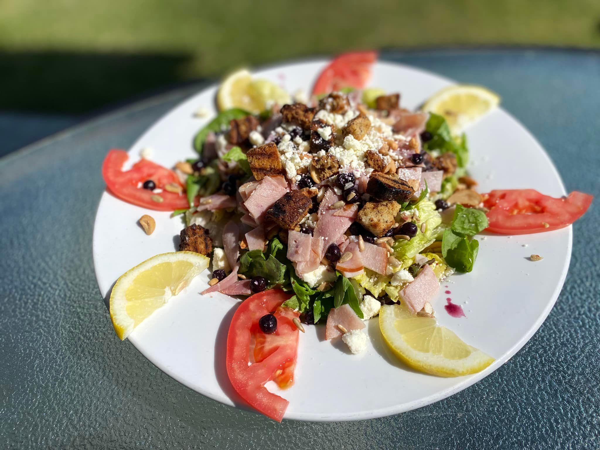 A white plate topped with a salad with tomatoes and lemon slices.
